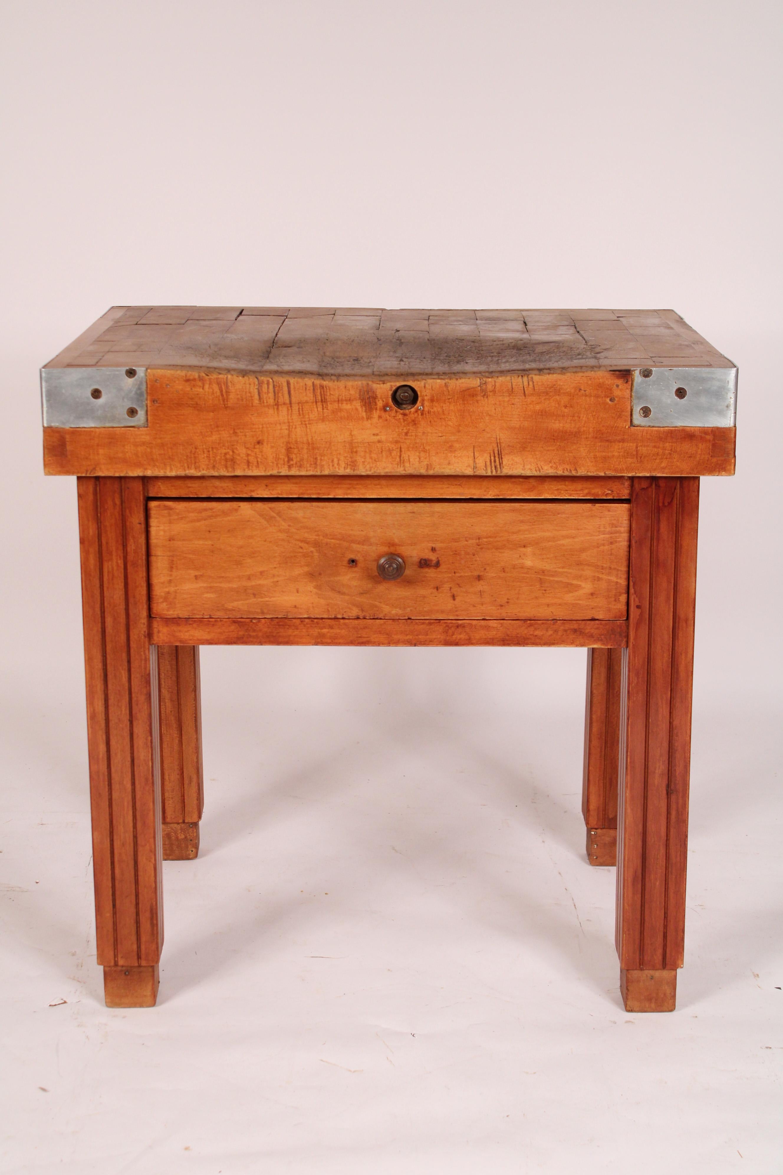 
Vintage butchers block table ,circa 1950s. With an overhanging butchers block top with metal brackets on the corners and a parquetry top, a dove tailed frieze drawer supported on fluted legs ending in block feet.