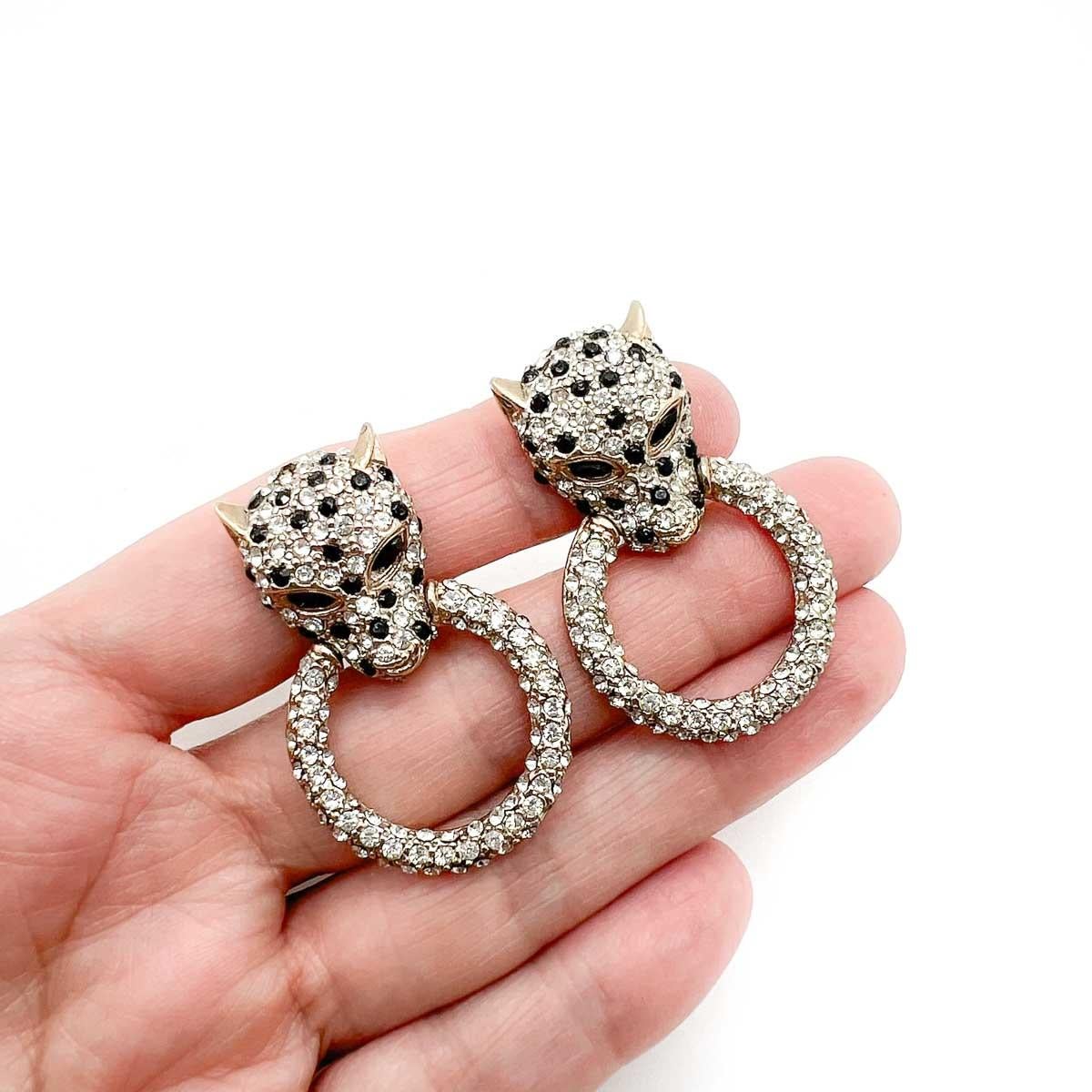 A Pair of Vintage Butler & Wilson Big Cat Earrings. Featuring leopard inspired heads holding a large door knocker style ring. Glistening with pave set crystals these beauties will amp up your style every time.

Butler and Wilson began in 1969