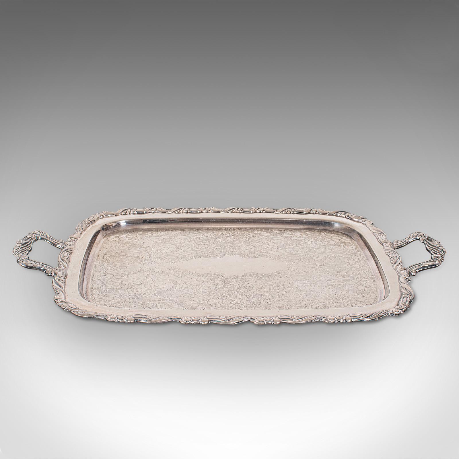 This is a vintage butler's serving tray. An American, silver plated tea platter by Oneida, dating to the mid-20th century, circa 1960.

Elegantly engraved service tray
Displays a desirable aged patina with minimal tarnish
Silver-plated with