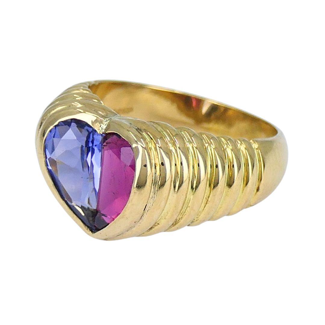 This vintage Bvlgari heart ring from the 1990s showcases the brand’s sculptural approach to color and geometry. Crafted in 18k yellow gold, the design centers on a heart motif divided into two pear-shaped faceted stones: one half is iolite, the