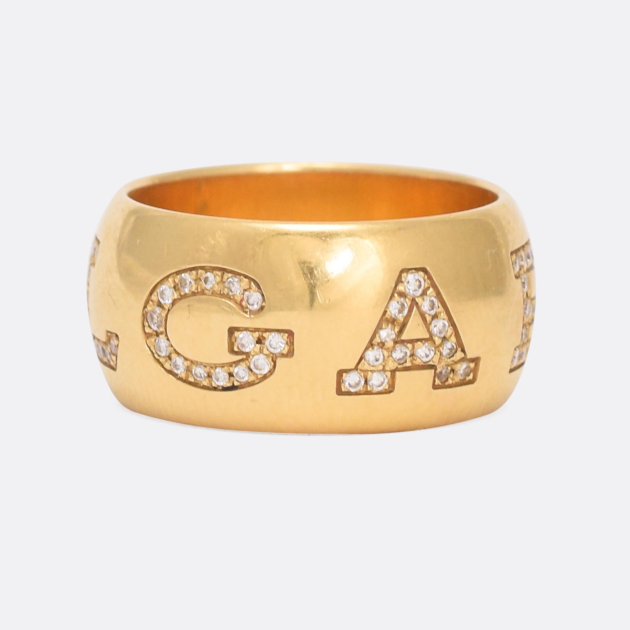 Vintage BULGARI ring dating from the 1980s. The iconic lettering (stylized with V in place of U, like the Romans did) wraps around the band; each letter studded with white diamonds. It's a wide band (1.0cm) and modelled in 18 karat gold, complete