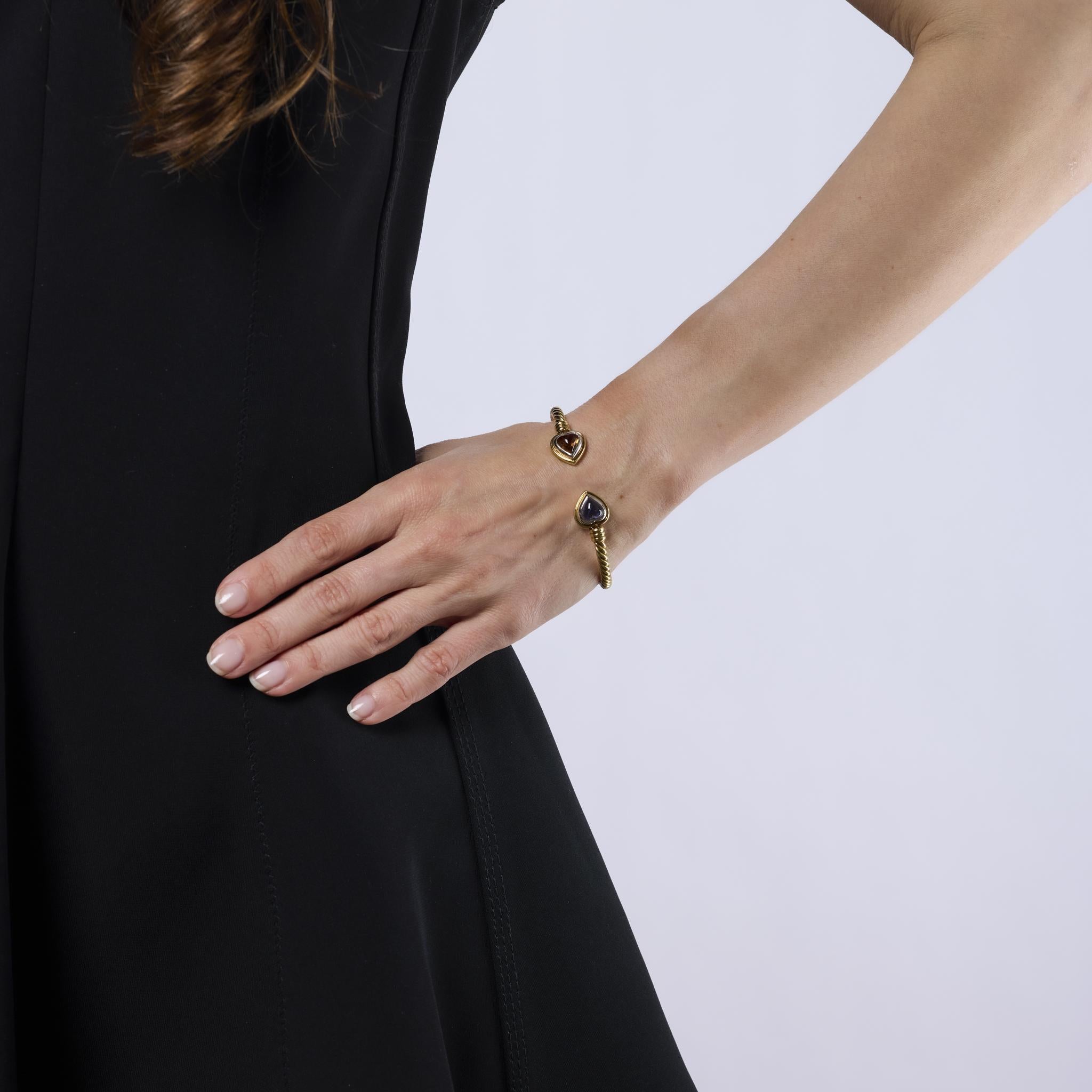 This bold vintage Bvlgari bracelet showcases two vibrant heart-shaped cabochon sapphires, one blue and one orange, set in luxurious 18k yellow and white gold. A striking 1980s design that radiates color, sophistication, and iconic Italian