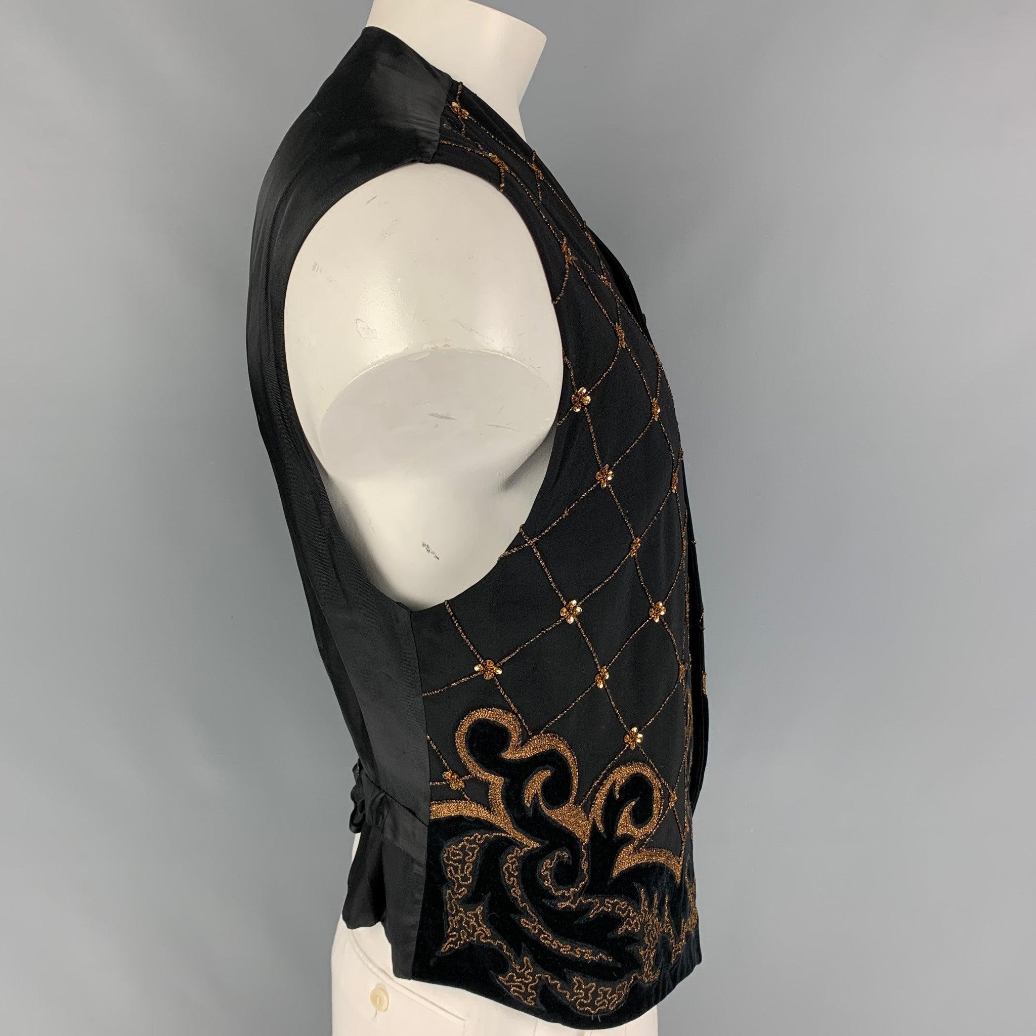 Vintage BYBLOS vest comes in a black wool featuring gold embroidered designs, velvet trim, back belt strap, and a buttoned closure. Made in Italy.
Very Good
Pre-Owned Condition. 

Marked:   52 

Measurements: 
 
Shoulder: 19.5 inches  Chest: 42