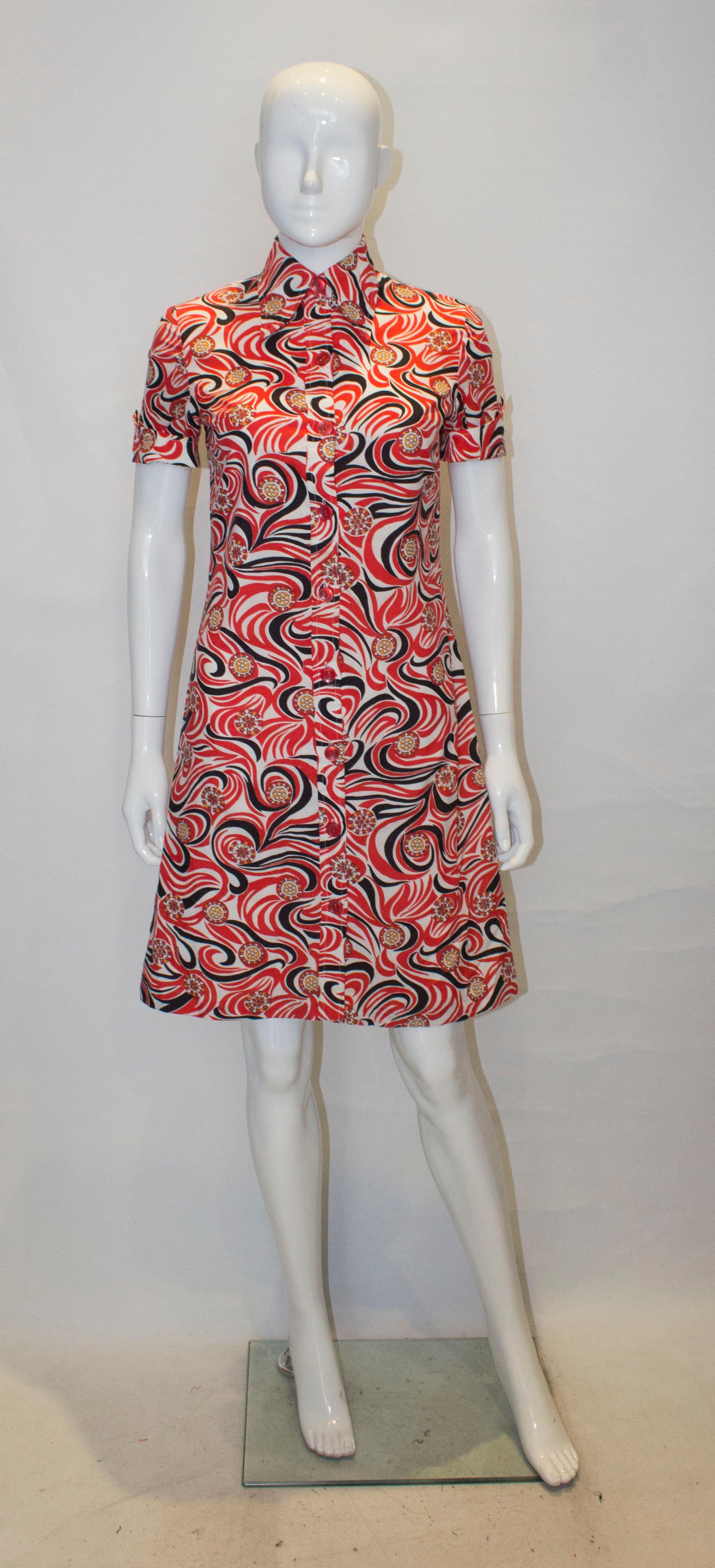 A vintage C & A shirt dress in a wonderful print of red, white , black and orange. The dress is fully lined, has a nine button opening and short sleaves.