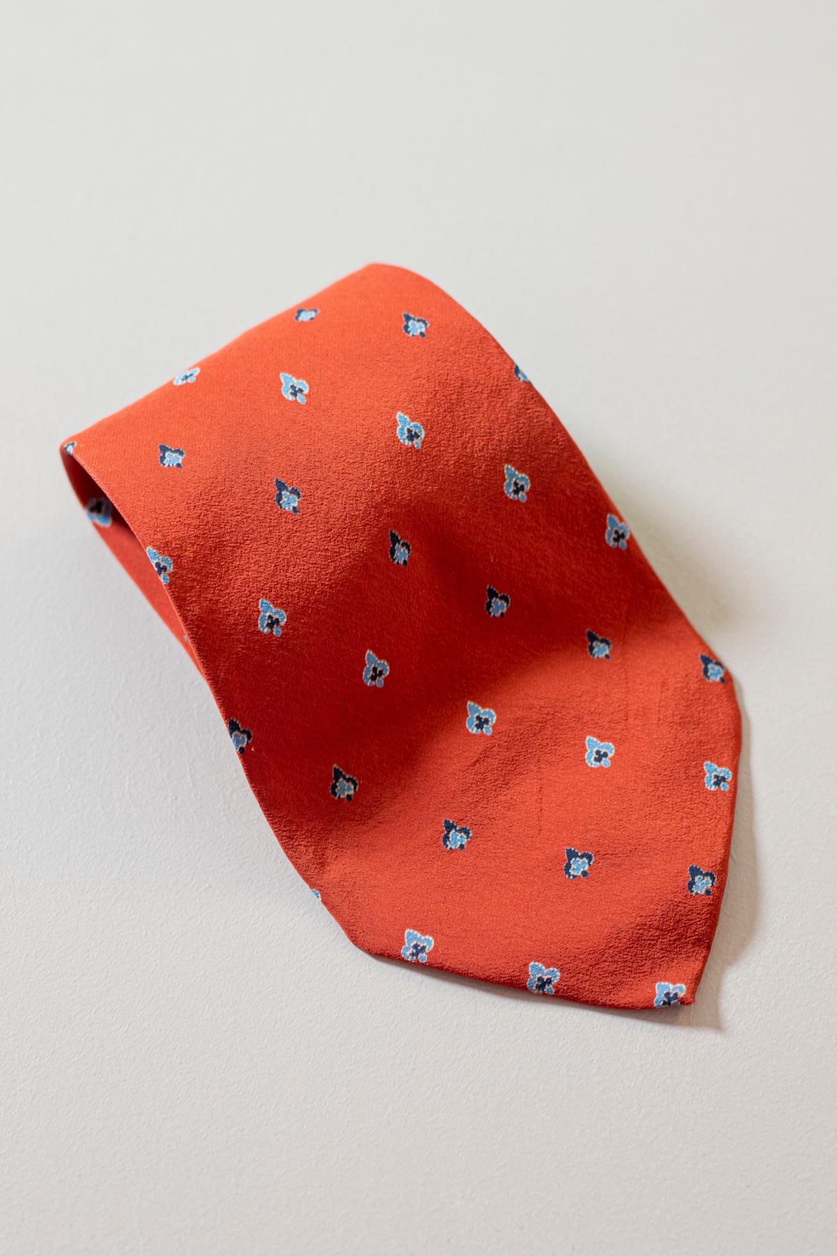 Elegant and vintage this tie is designed by C. Bardelli, it is made of silk. Decorated with small blue lily symbols on a red background. With its inimitable character and colors, this tie, thanks to its elegance, is able to give you an impeccable