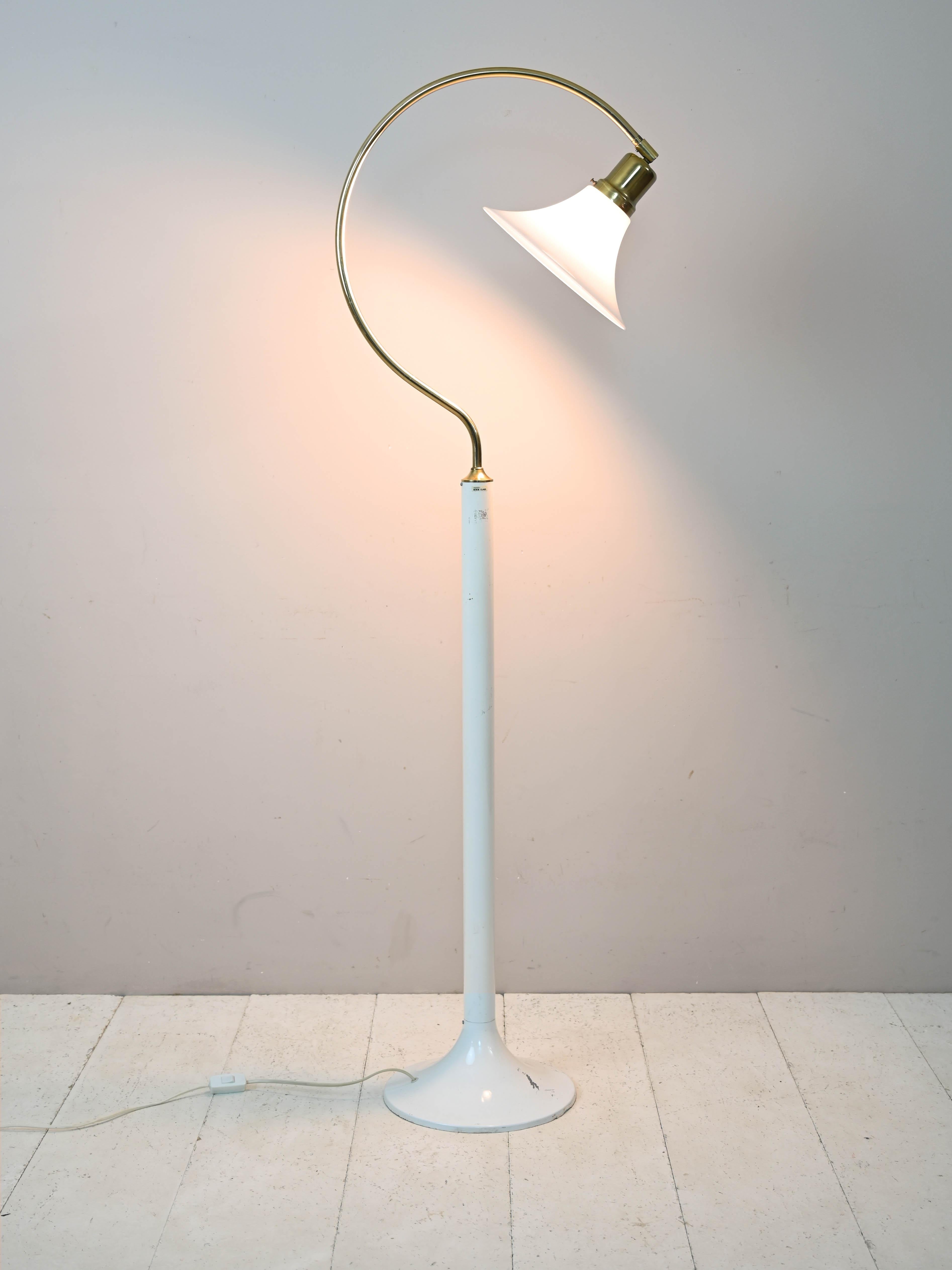 Eigenartige originelle skandinavische Lampe aus Kunststoff und Metall.

Dieses Möbelstück zeichnet sich durch die originelle Form des Stiels aus, der am Ende die Form eines C annimmt und aus goldenem Metall besteht.
Der Hartplastikschirm ist weiß