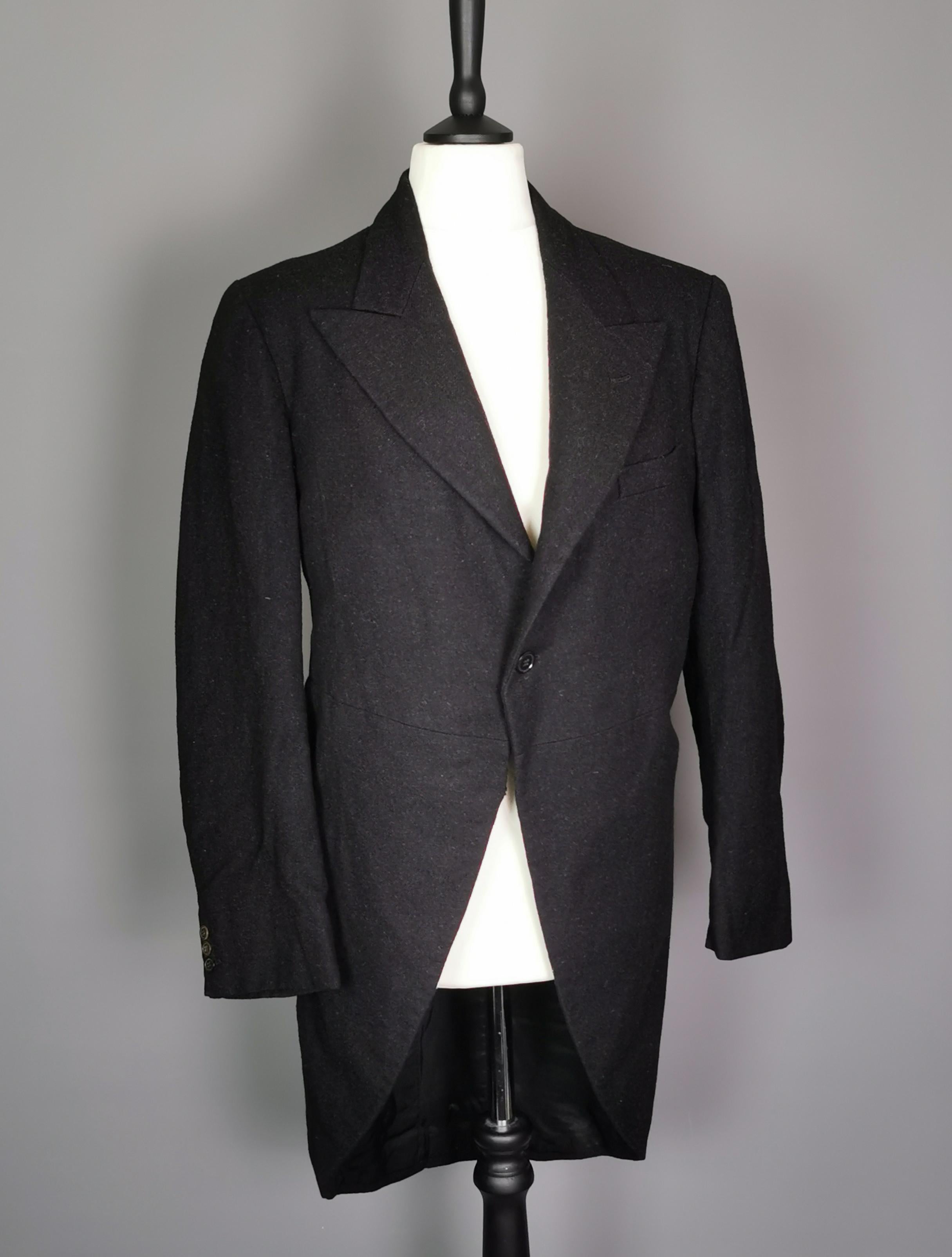 A stylish Gentleman's, vintage c1930s, black wool tailcoat.

Made in England from a strong and thick wool blend knit, it has a graduated cutaway front and fastens with a single button.

It has black plastic buttons up the cuffs and to the