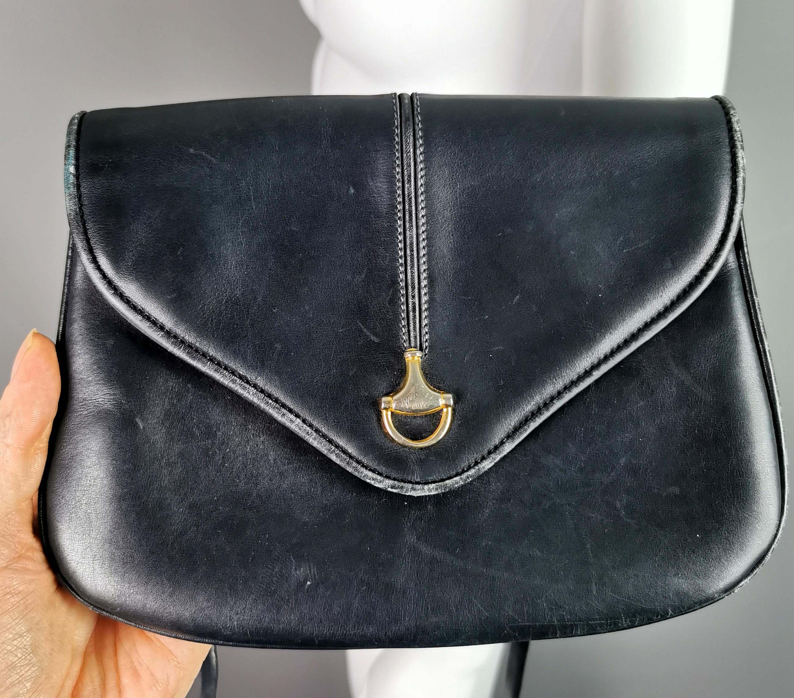 A rare vintage c1960s Gucci navy leather handbag.

It is a shoulder or Crossbody style bag, small sized with a long strap, the front has an envelope style closure with a gold tone half horsebit embellishment.

The long leather handle can be detached