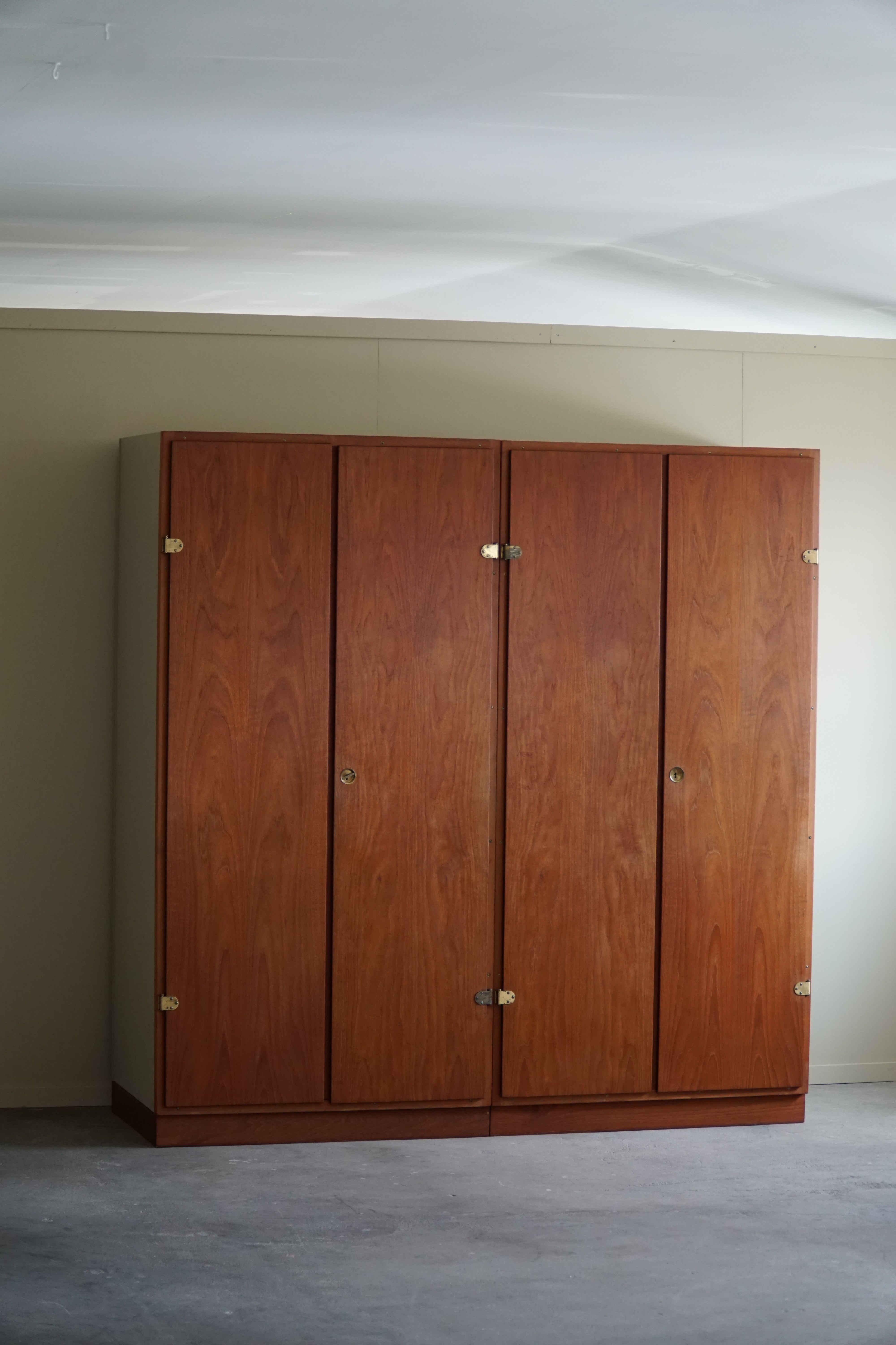 A classic wardrobe with upper cabinets in oregon pine with fronts in teak and leather handles, known as 'Boligens Byggeskabe', designed by Børge Mogensen & Grethe in 1956. The wardrobe's design reflects the Danish modern style, characterized by