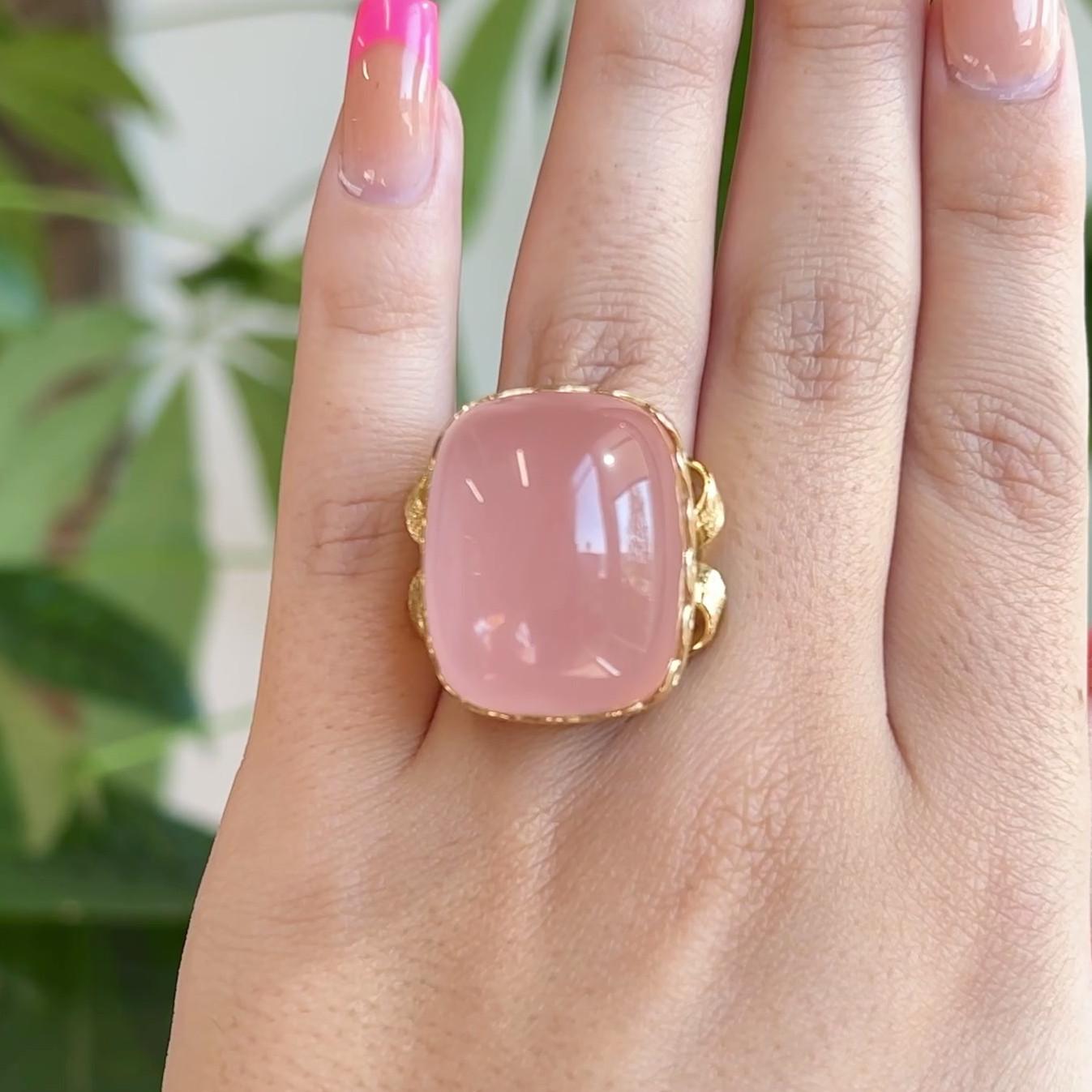 One Vintage Cabochon 77.40 Carat Rose Quartz 18 Karat Yellow Gold Textured Wave Ring. Featuring one cabochon cut rose quartz of approximately 77.40 carats. Crafted in 18 karat yellow gold with purity marks. Circa 1980. The ring is a size 7 and may