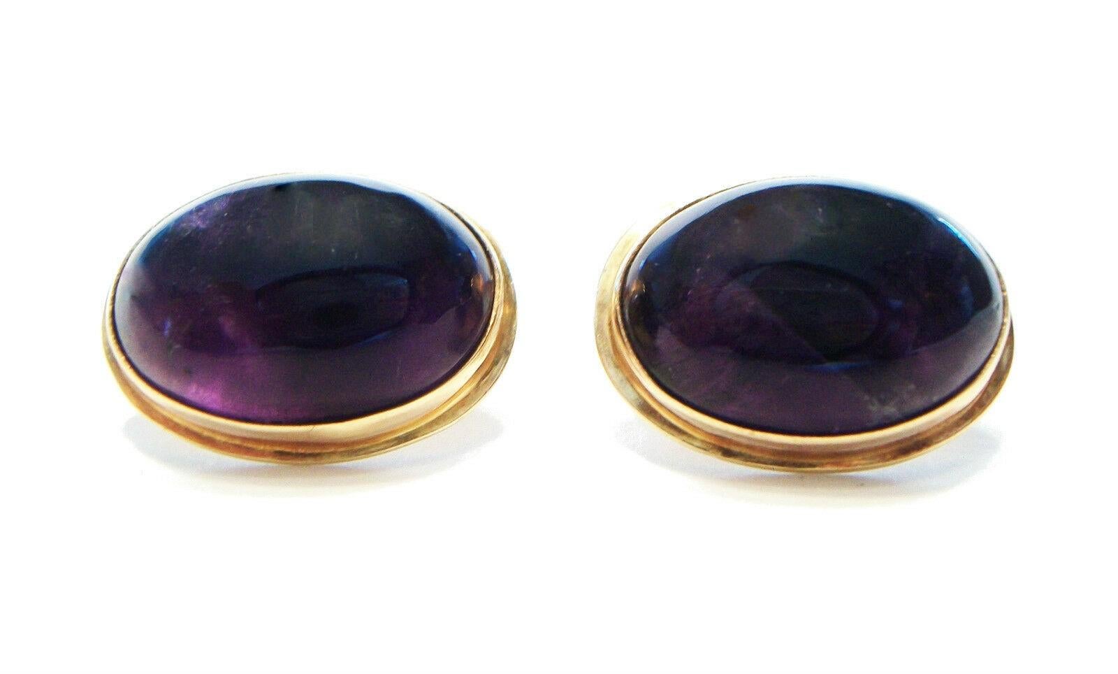 Vintage oval cabochon Amethyst (each approx. 12.4 carats - 18 mm. x 12 mm. x 7 mm. deep) & 14K yellow gold cufflinks - bezel set gemstones - bench made/hand made - unsigned - each toggle stamped 14K - late 20th century.

Excellent vintage condition