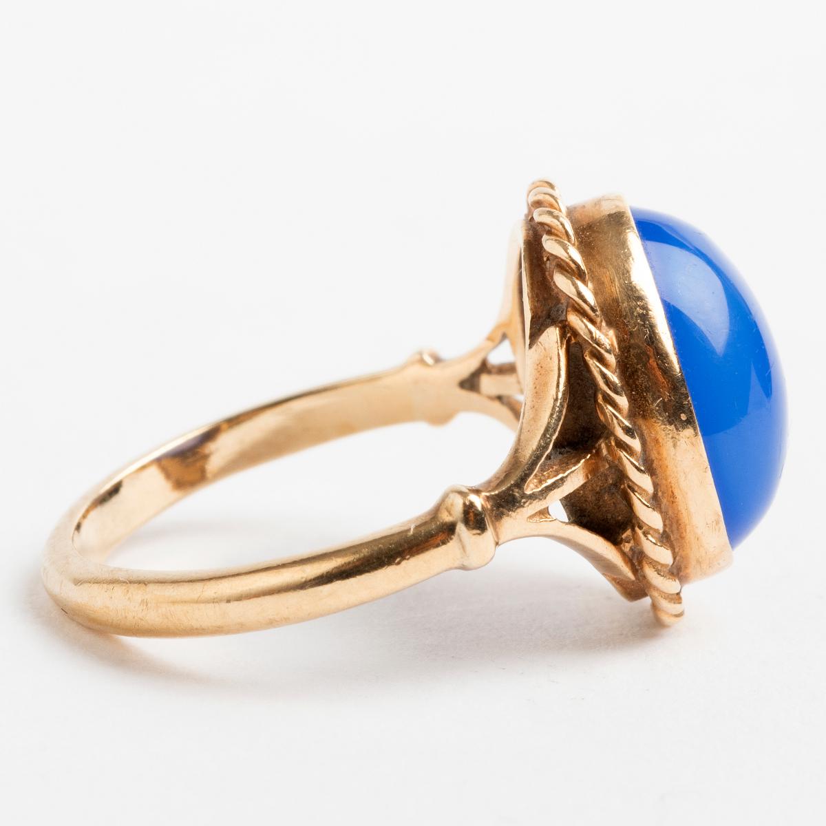 Our vintage cabochon blue chalcedony dress ring exudes period appeal., the stone in a rubber setting with plaited surround in 9k yellow gold. We date this ring to c mid 1960s. The ring size is L.

A unique piece within our carefully curated Vintage