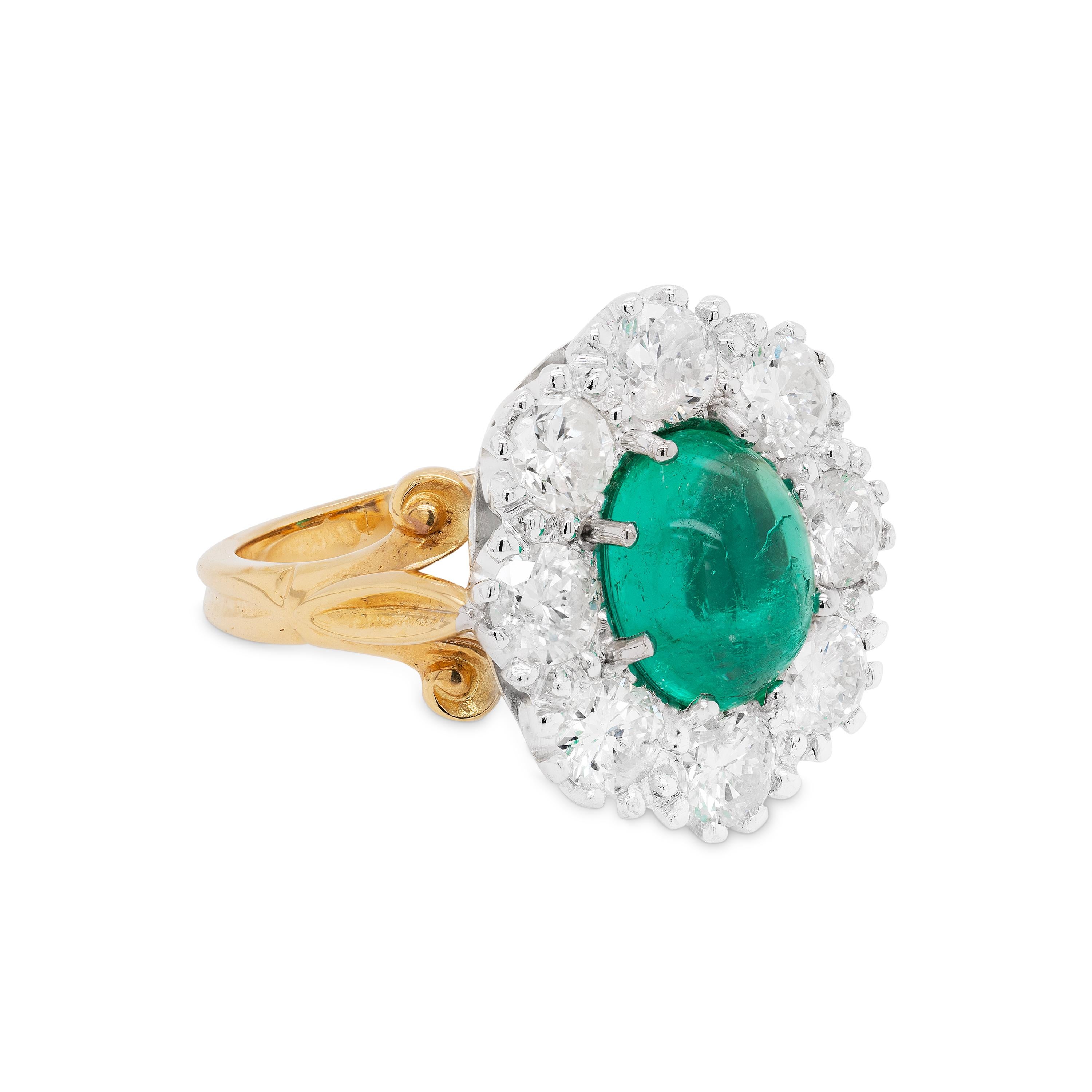 This wonderful coronet cluster engagement ring features a cabochon emerald of a beautiful colour and great lustre  weighing approximately 2.00ct, mounted in an eight claw, open back setting. The gorgeous stone is surrounded by 8 round brilliant cut