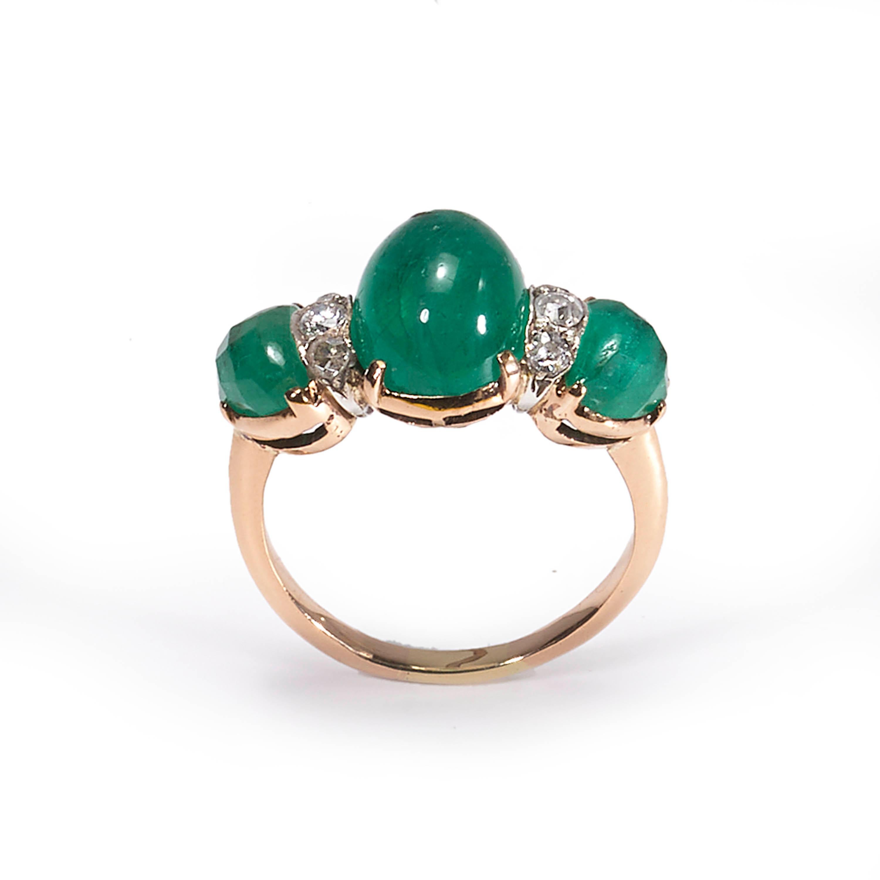 A vintage three stone ring, set with a central cabochon-cut emerald, weighing an estimated 2.80 carats, with a fancy faceted emerald set to each shoulder, weighing an estimated 1.60 carats each, with a total of six round brilliant-cut diamonds set