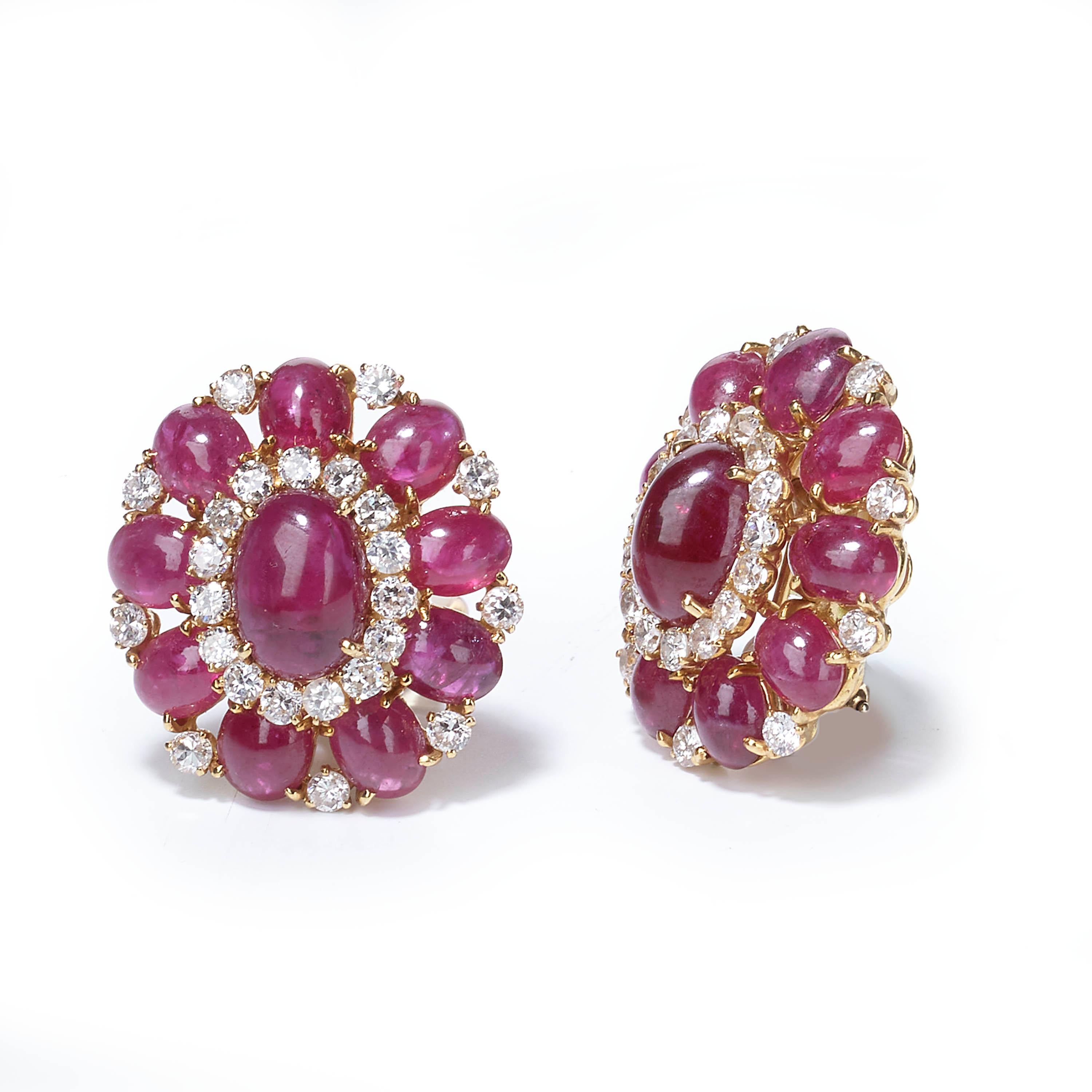 A pair of vintage earrings, consisting of two oval-shaped clusters, each centrally set with an oval, cabochon-cut ruby and surrounded by a further nine rubies, and twenty-four round brilliant-cut diamonds, all claw set and mounted in 18ct yellow