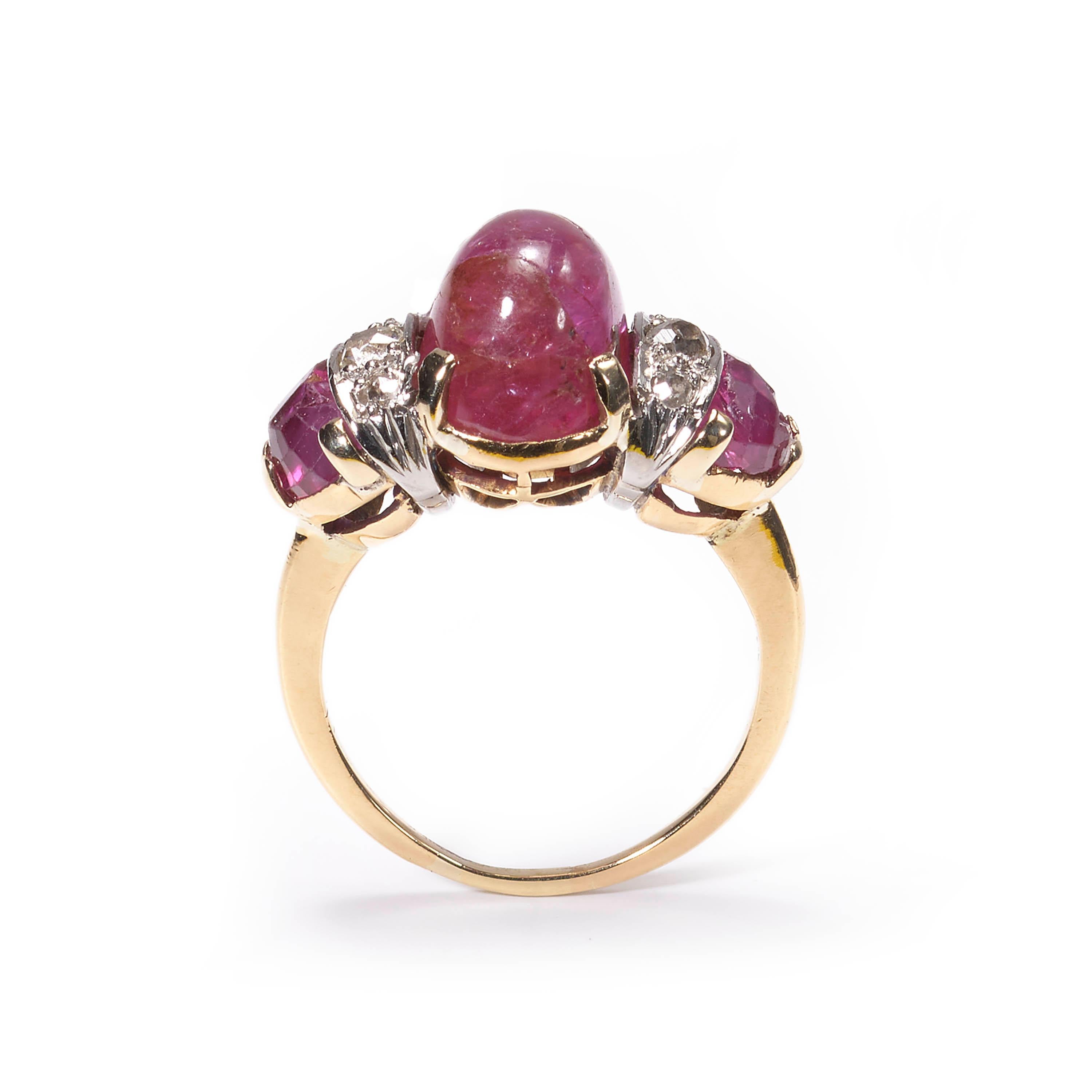A vintage three stone ring, set with a central cabochon-cut ruby, weighing an estimated 4.80 carats, with a fancy faceted ruby set to each shoulder, weighing an estimated 1.60 carats, with a total of six round brilliant-cut diamonds set in-between,