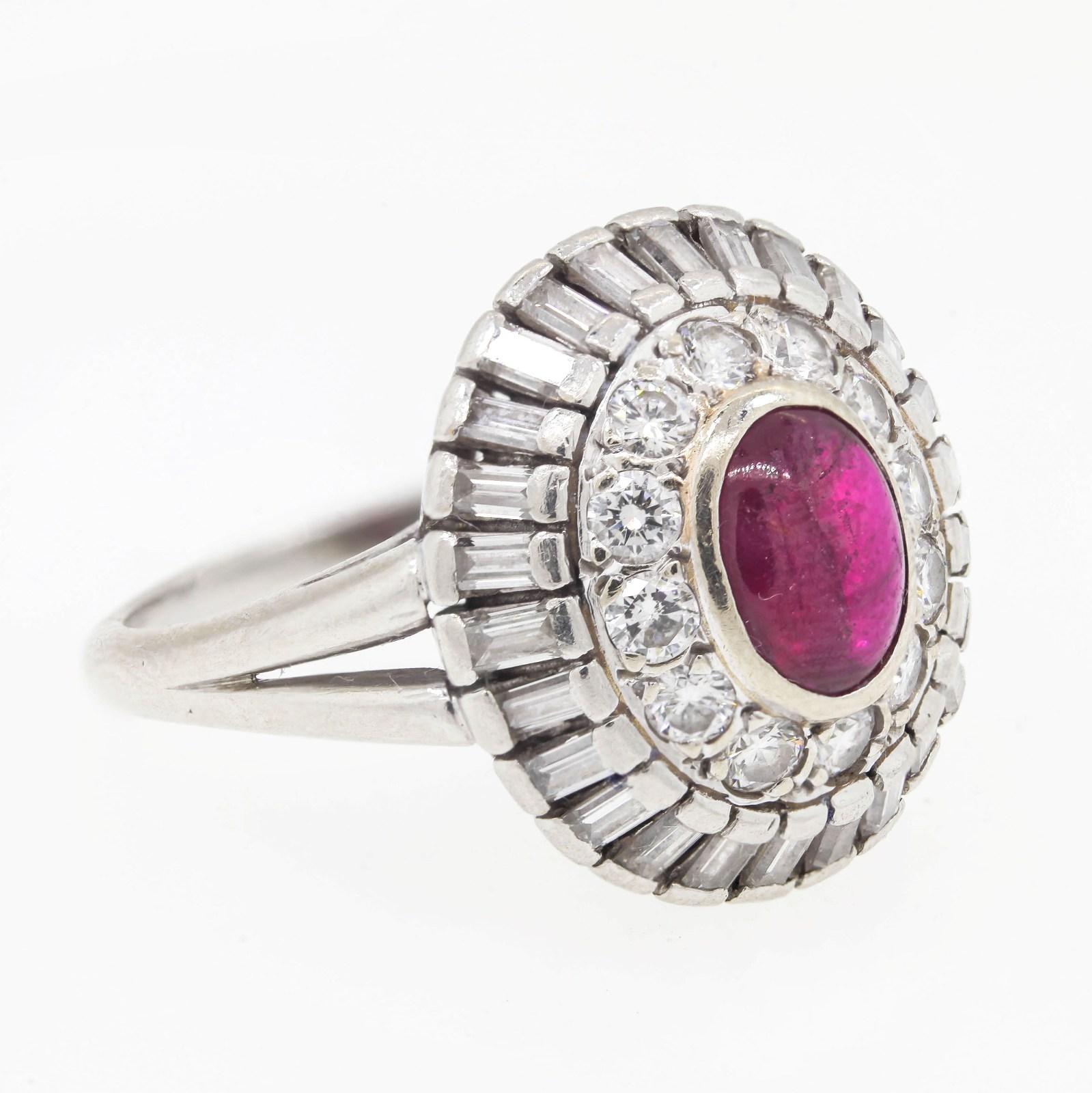 This platinum, vintage dome designed ring, flashes a bezel set 0.60 carat cabochon red Ruby in its center.  The Ruby is surrounded by twelve Round Brilliant cut Diamonds and twenty twenty six Baguette cut Diamonds, all weigh 1.85 carats and