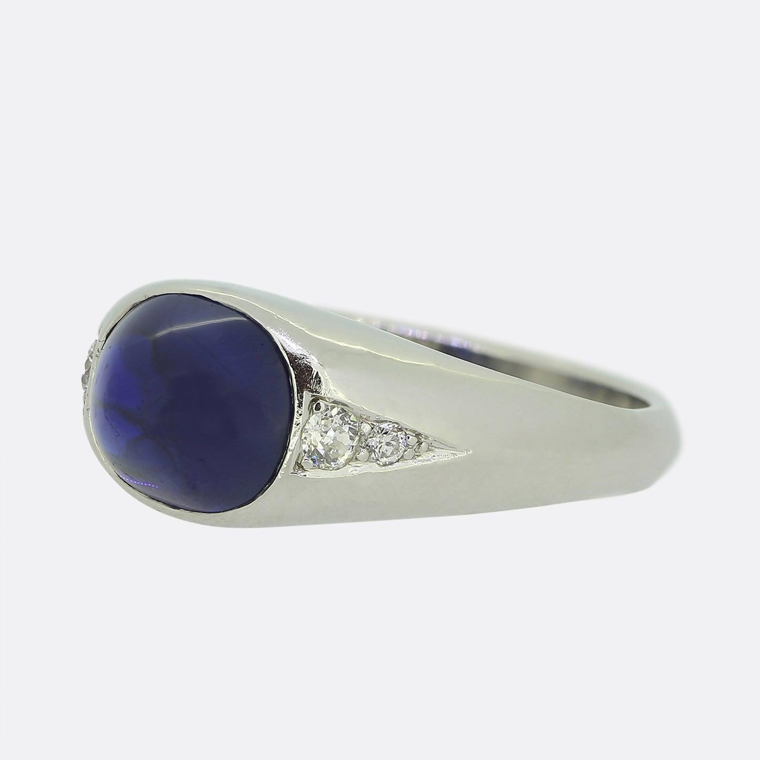 Here we have a fabulous sapphire and diamond ring. A remarkable natural sugarloaf cabochon sapphire possessing a rich royal blue colour tone sits at the centre the centre of the face and is flanked on either shoulder by a duo of round faceted old