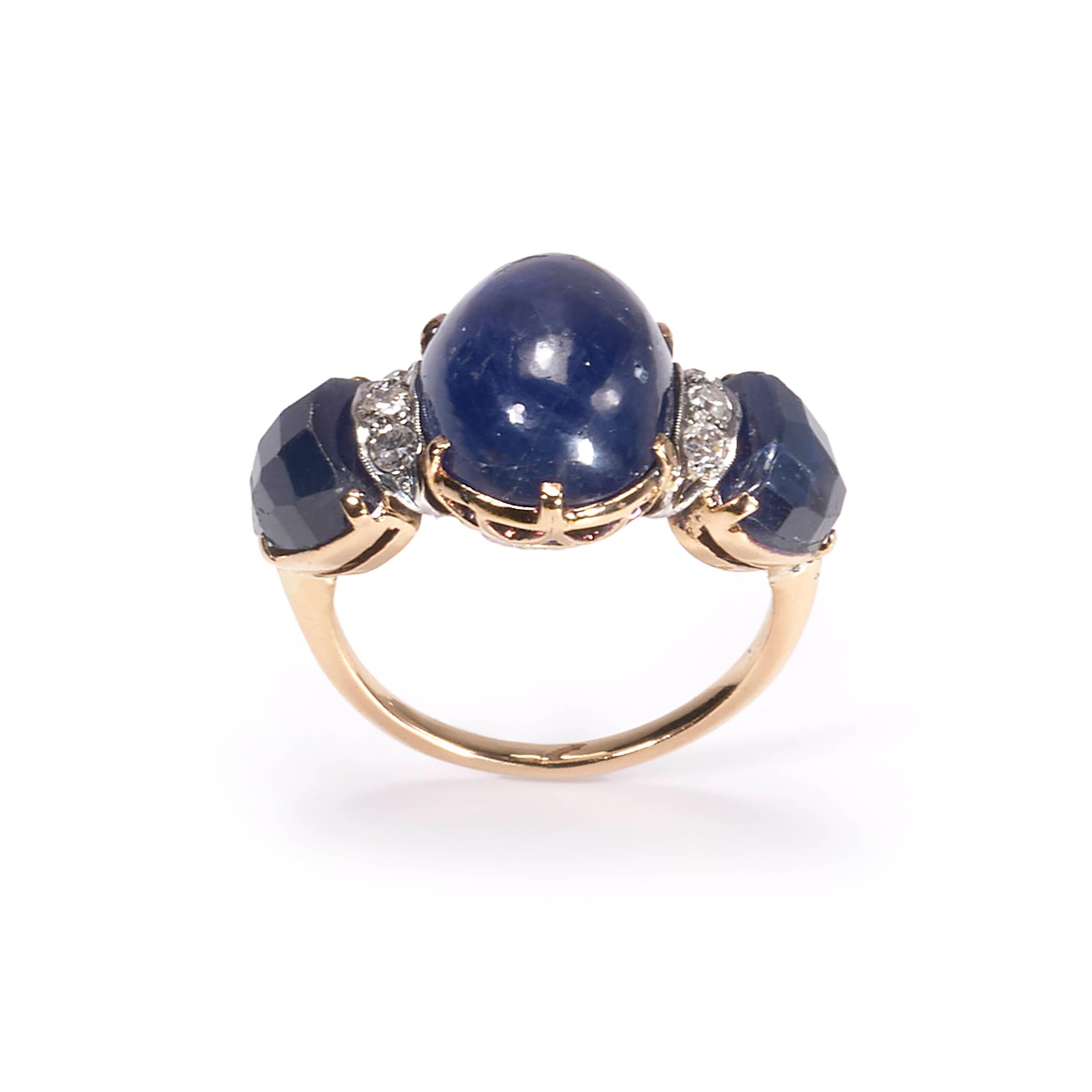 A vintage three stone ring, set with a central cabochon-cut sapphire, weighing an estimated 9.00 carats, with a fancy faceted sapphire set to each shoulder, weighing an estimated 4.00 carats, with a total of six round brilliant-cut diamonds set