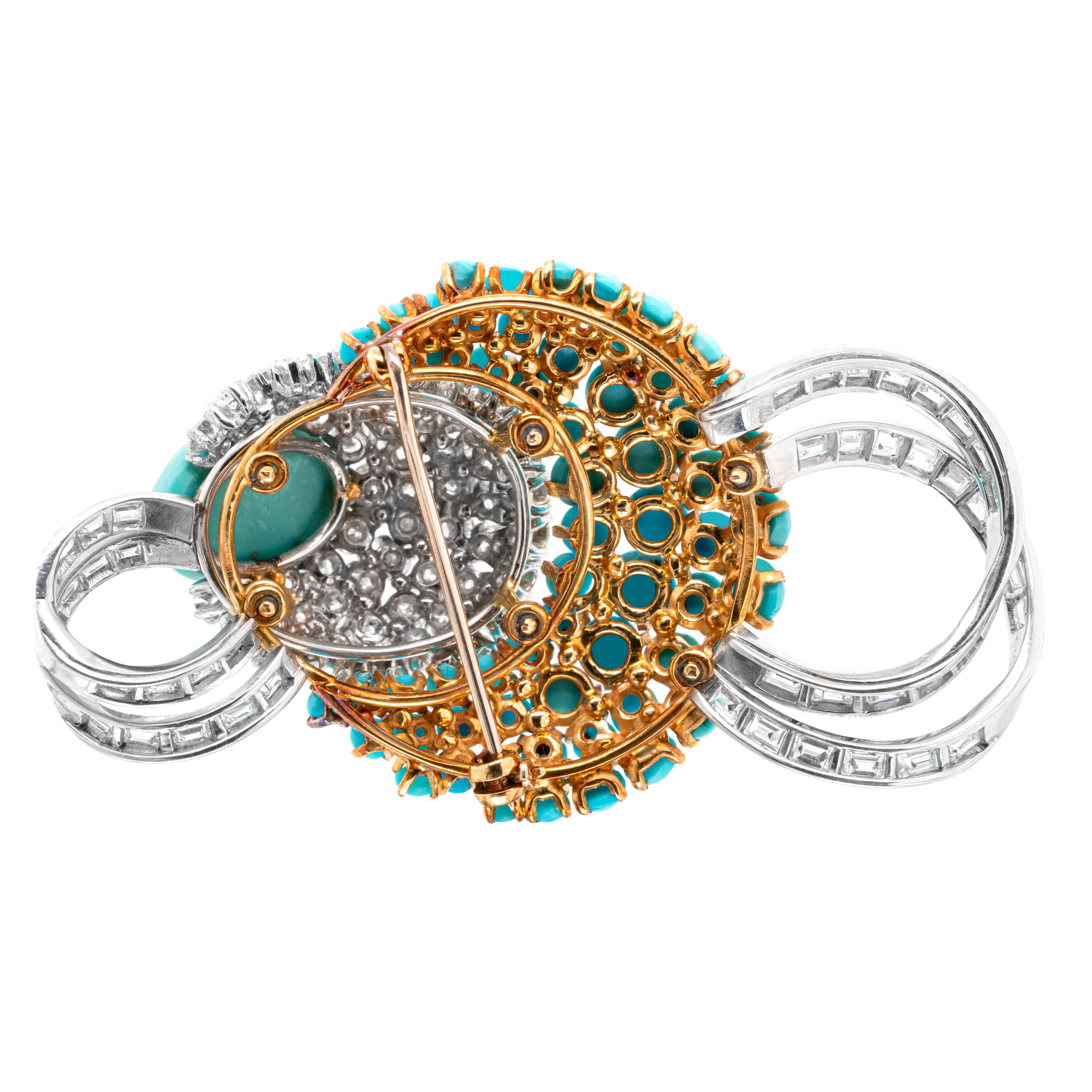 This unusual brooch features a 15x11mm oval shaped cabochon turquoise, claw set within five graduating half moon shaped rows of 63 round brilliant cut diamonds, all claw set in 18 carat white gold mounts. The five diamond rows are followed by a