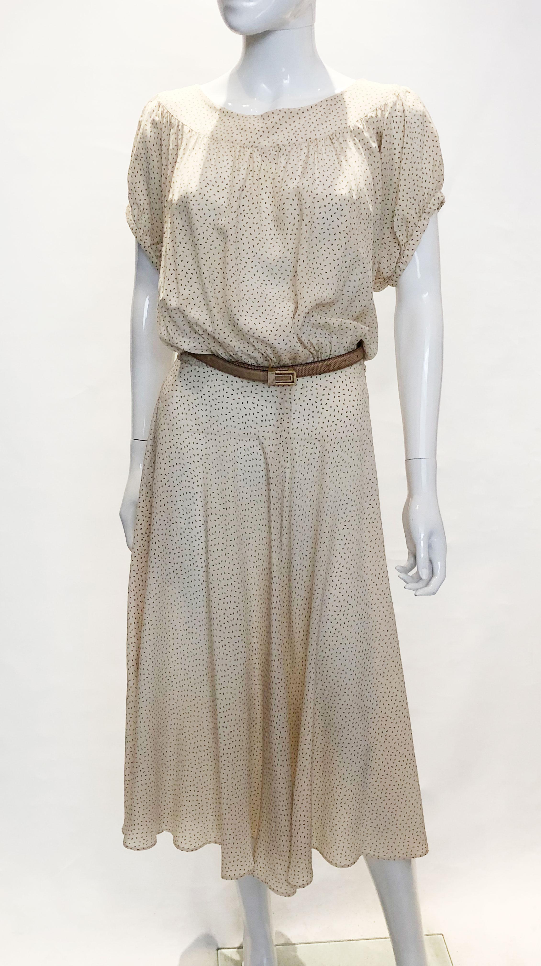 A pretty silk dress by Cacharel from 1978, and featured in Vogue from that year. It has a cream background and brown print detail with  a round neckline, with gathered short sleaves and a side opening .