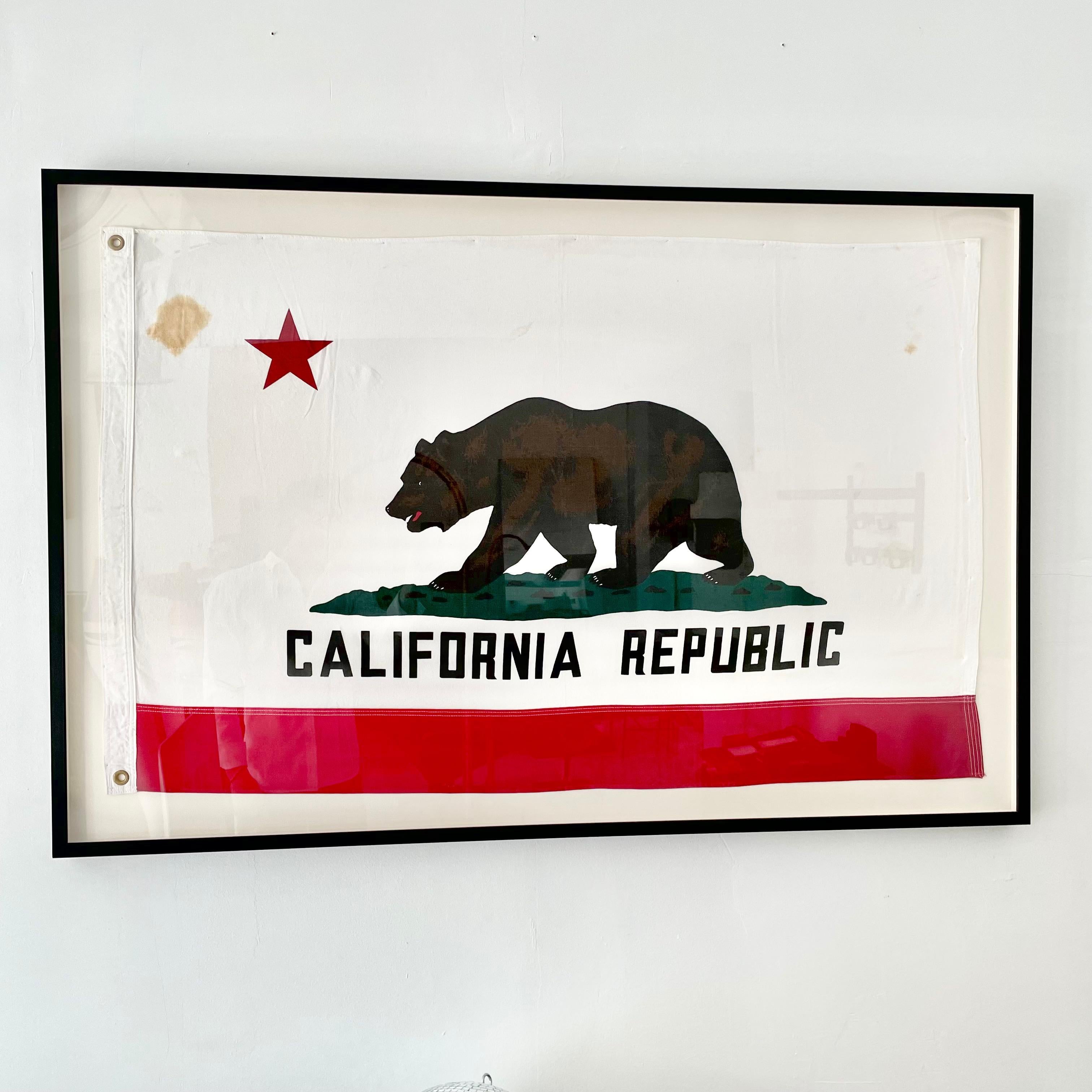 Vintage California Republic flag made in the 1960s. Made of thick cotton. Great coloring. Fun piece of California history. Newly mounted on a linen shadow box, with black frame and plexiglass. Stain at top right and left. Cool piece of art. Only one