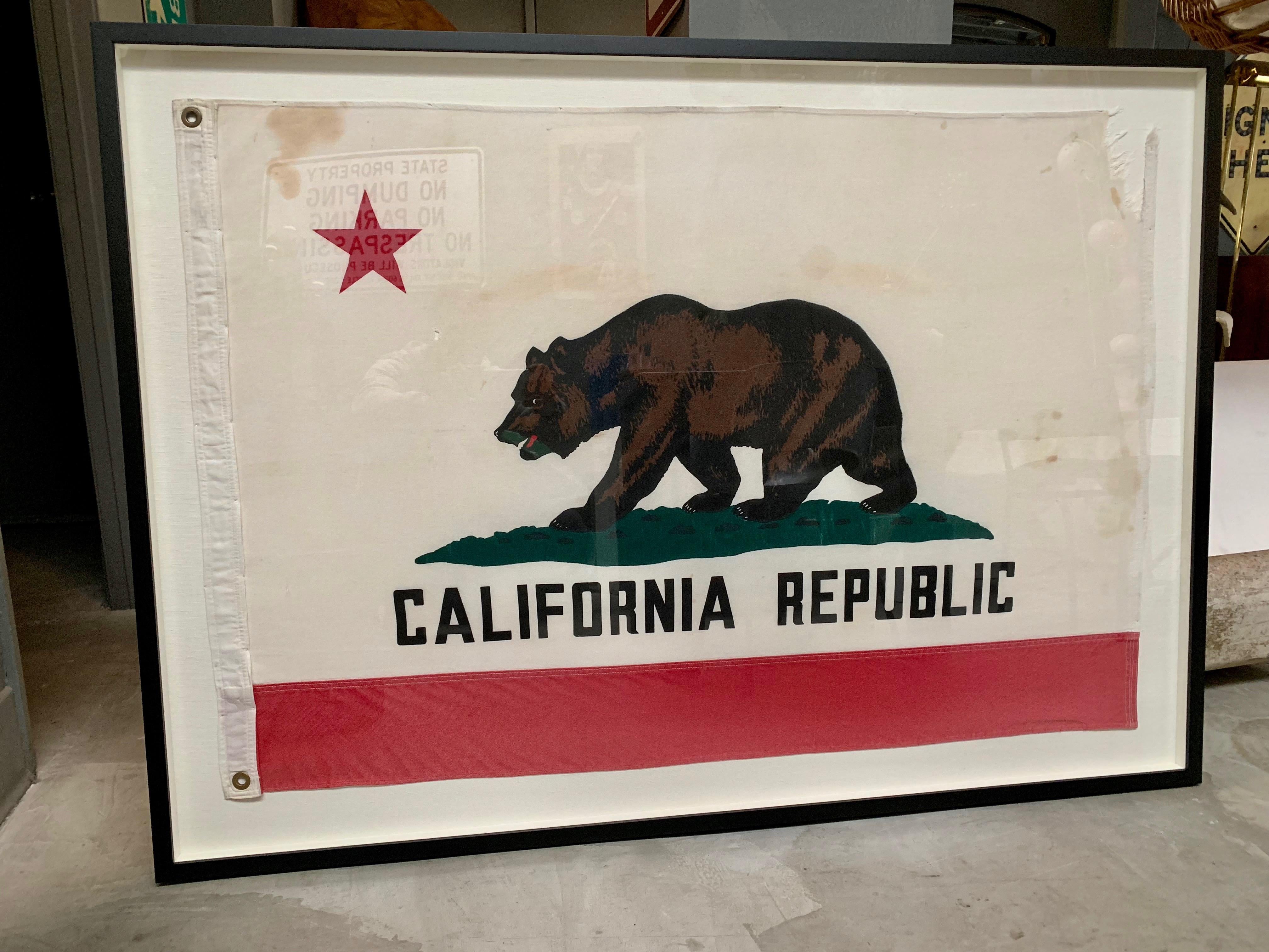 Fun piece of California history. Vintage California Republic flag made in the 1960s. Made of thick linen. Newly mounted on a linen shadow box, with black frame and plexiglass. Rip to top right corner and some staining. Cool piece of art. Only one