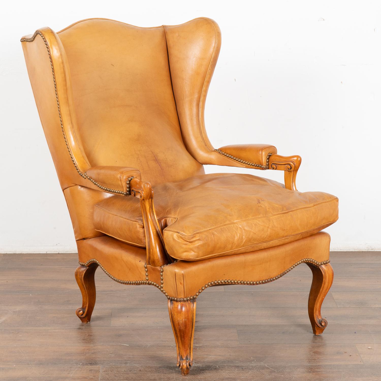 Vintage brown leather wingback arm chair with classic nail head trim resting on cabriolet feet.
Carmel colored leather shows stains to seat, some cracking at center lower back.
Sold in vintage used condition. Frame is solid/stable and sits