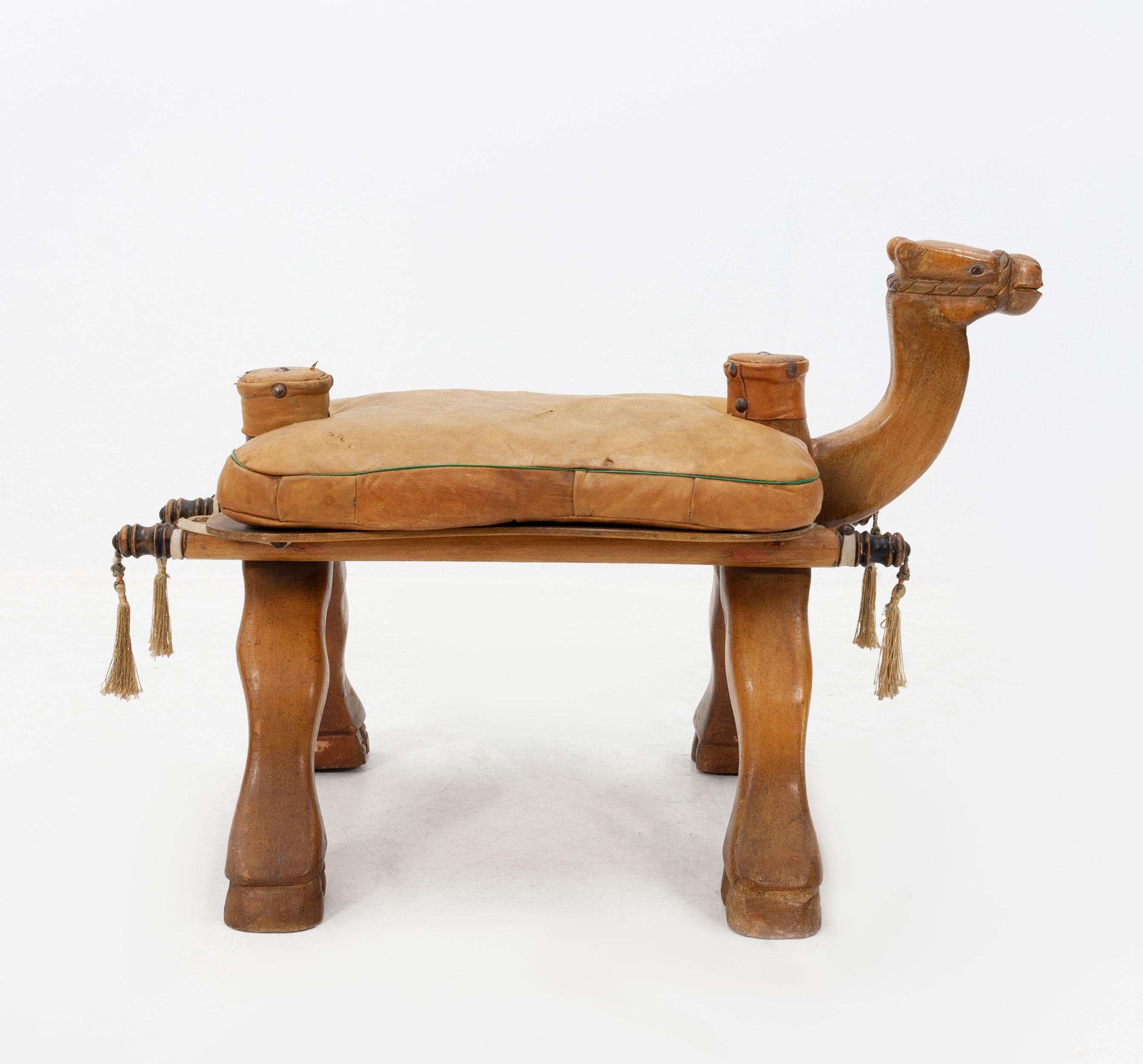 Camel saddle stool, 1960s Egypt. Look at his little face. Very nice carving. To rest your feet
or to sit on. Wooden camel comes with a leather cushion. Still with all his tassels. Lovely piece good vintage condition.







 