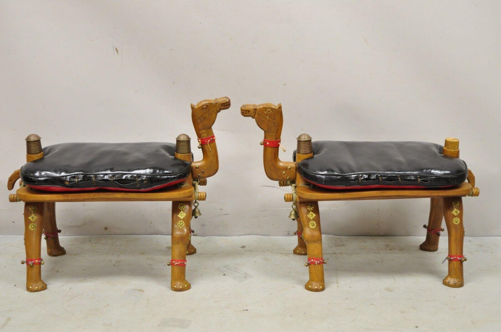 Vintage camel saddle stools carved wood black/red cushions - a pair. Item features a reversible pillow cushion (black/red), carved wood base, metal accents, very nice vintage pair, great style and form. circa mid to late 20th century. Measurements:
