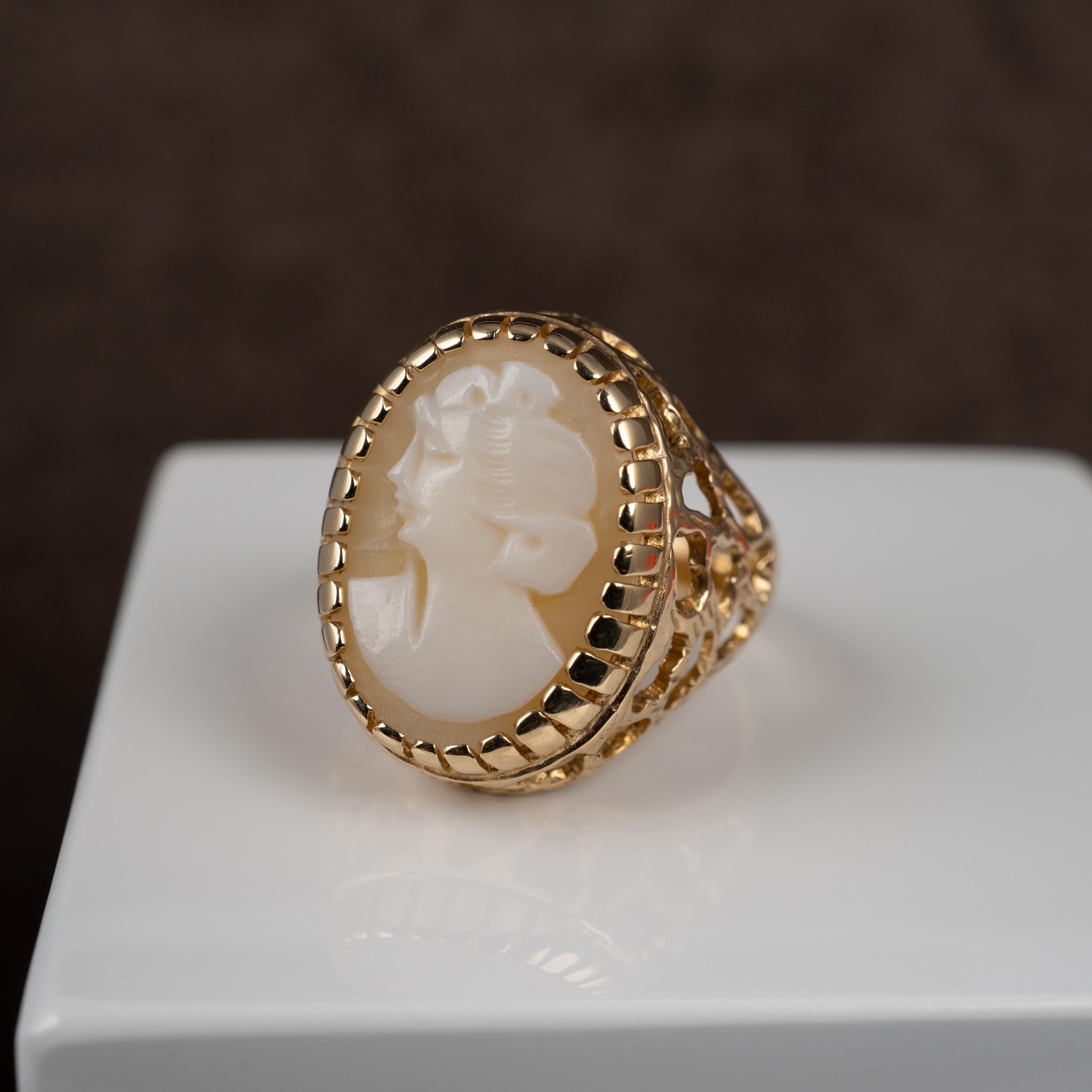 A superb 1970s vintage cameo ring features an open pierced decorative basket setting. Made in 9 karat yellow gold, the oval cameo is nicely crafted with bas-relief raised white demur looking female portrait. The gold setting and shoulders are