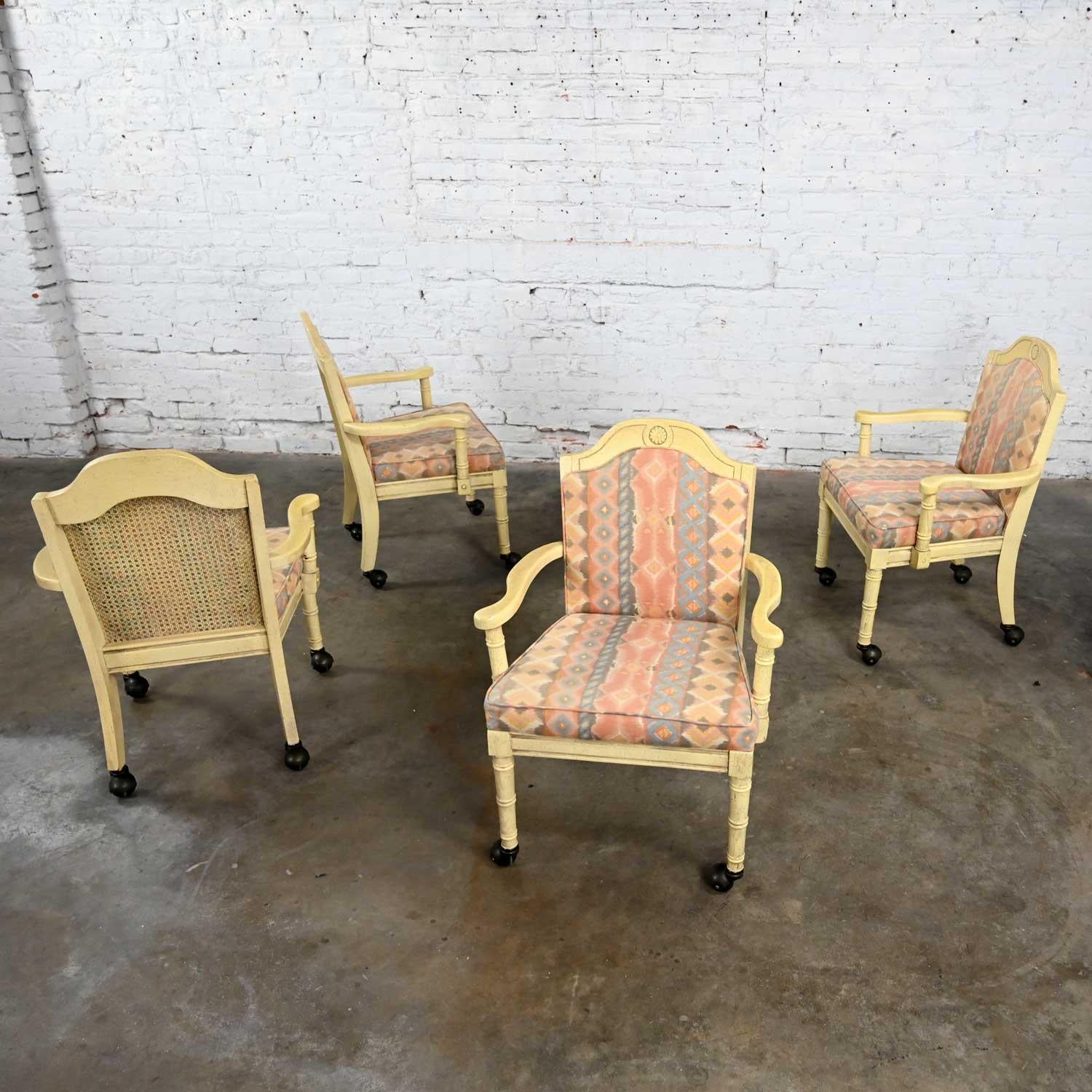 Stunning vintage Campaign or French Country rolling game chairs set of 4 by Burlington House Furniture. Comprised of antique white painted wood frames, upholstered seat and back cushions in the original pastel Southwestern fabric, cane seat backs,