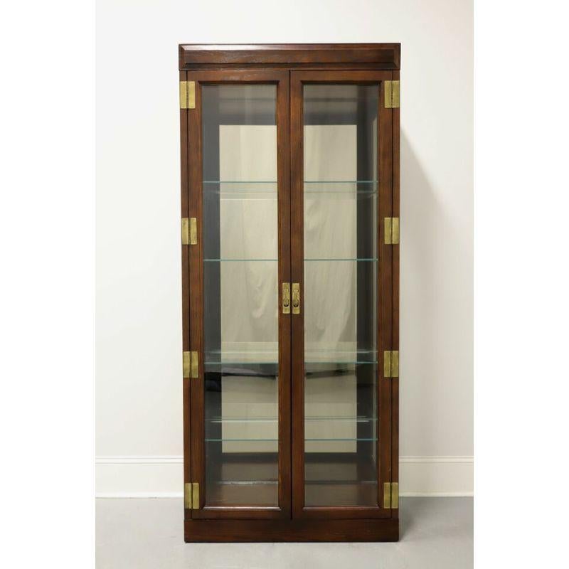 A Campaign style curio cabinet by Jasper Cabinet Company. Oak, brass hardware, dual beveled glass front doors and side panels. Features lighted interior cabinet with mirrored back and four adjustable plate grooved glass shelves. Made in Jasper,