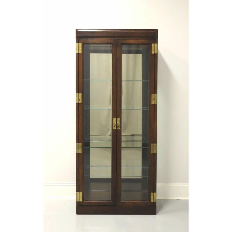 A Campaign style curio cabinet by Jasper Cabinet Company. Oak, brass hardware, dual beveled glass front doors and side panels. Features lighted interior cabinet with mirrored back and four adjustable plate grooved glass shelves. Made in Jasper,