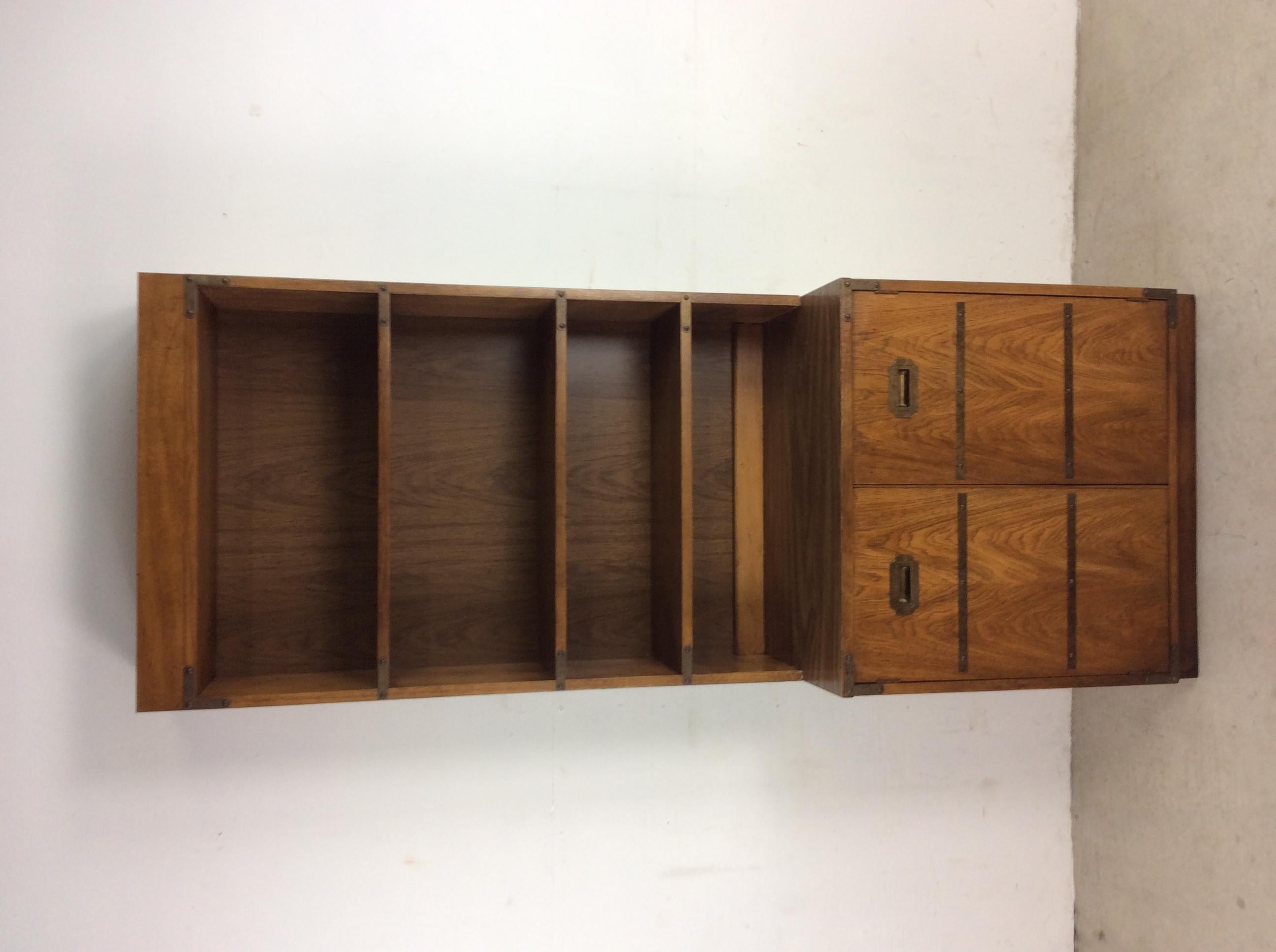 This 1970s vintage campaign style shelving unit features pressed wood construction, oak veneer with original finish, two piece design, three shelves up top (not adjustable), and two cabinet doors with interior shelf down below.??Matching campaign