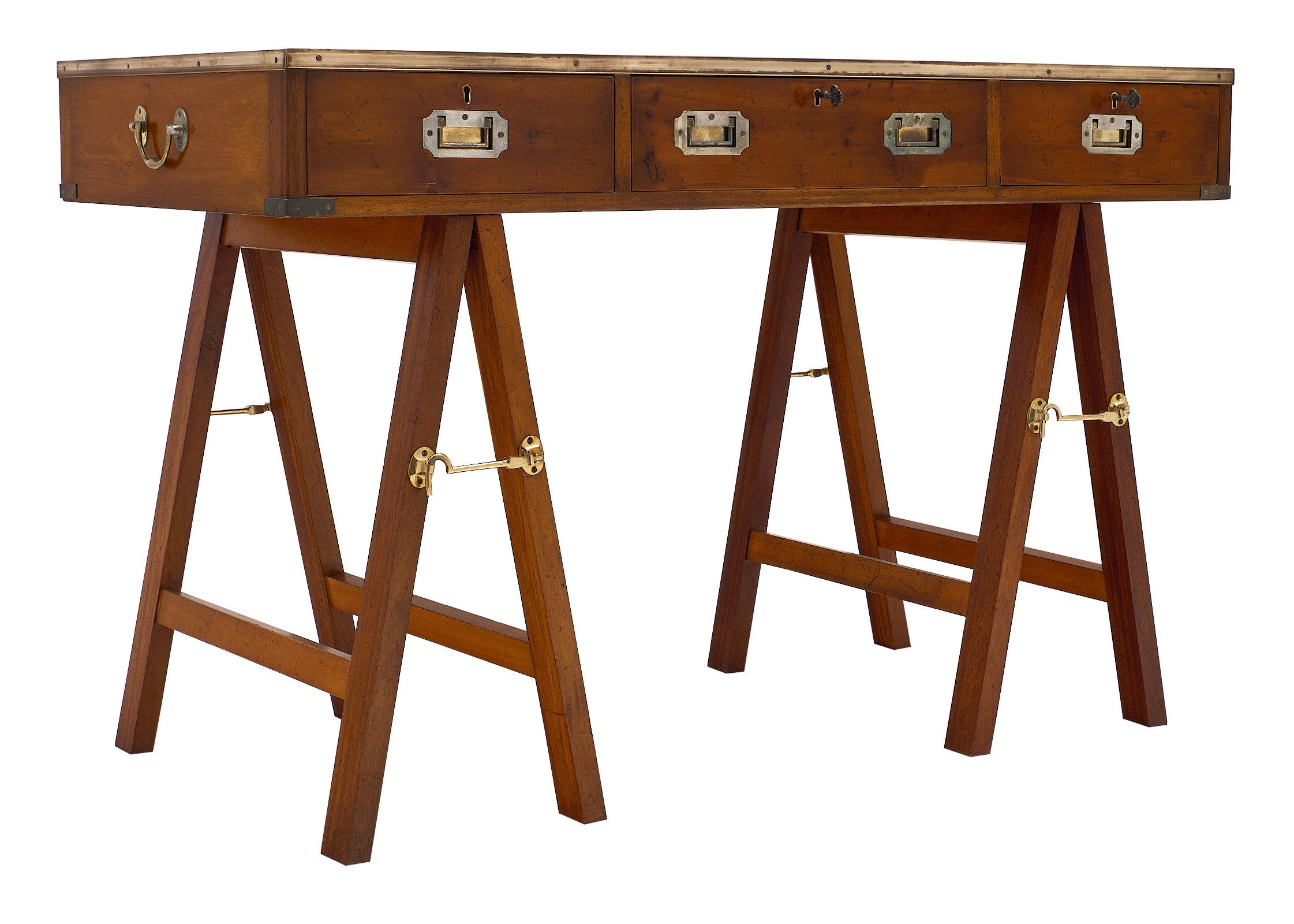 A fun, versatile Campaign style vintage writing desk with three dovetailed drawers and inserted solid brass handles. Brass trim highlights this solid piece. The desk is supported by A-frame stands connected with hooks. It features a beautiful gold