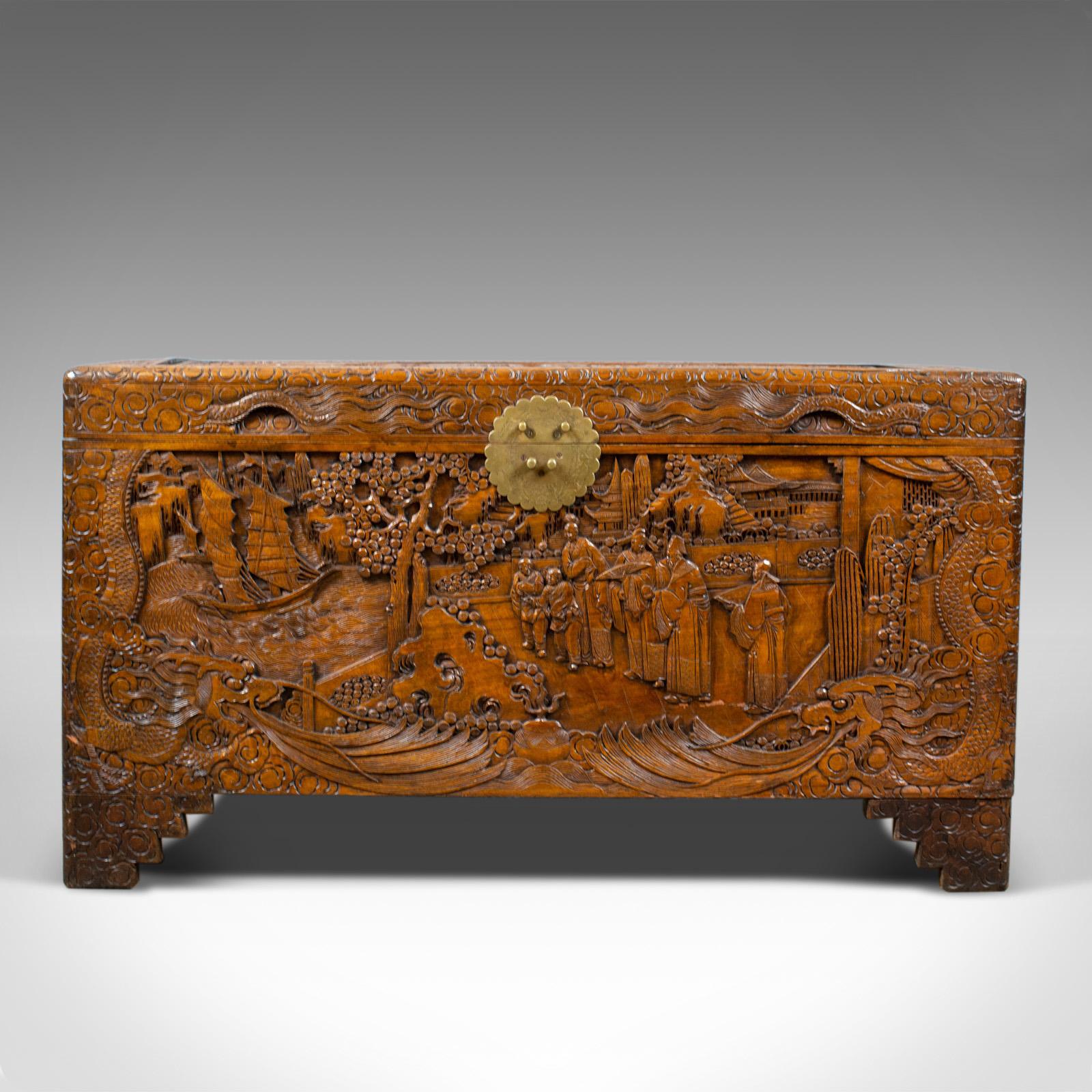 This is a vintage camphor wood chest with oriental carved scenes. A trunk dating to the early 20th century, circa 1940.

Fabulously decorated with profusely carved panels
Framed in geometric swirled borders
Standing upon typical step bracket