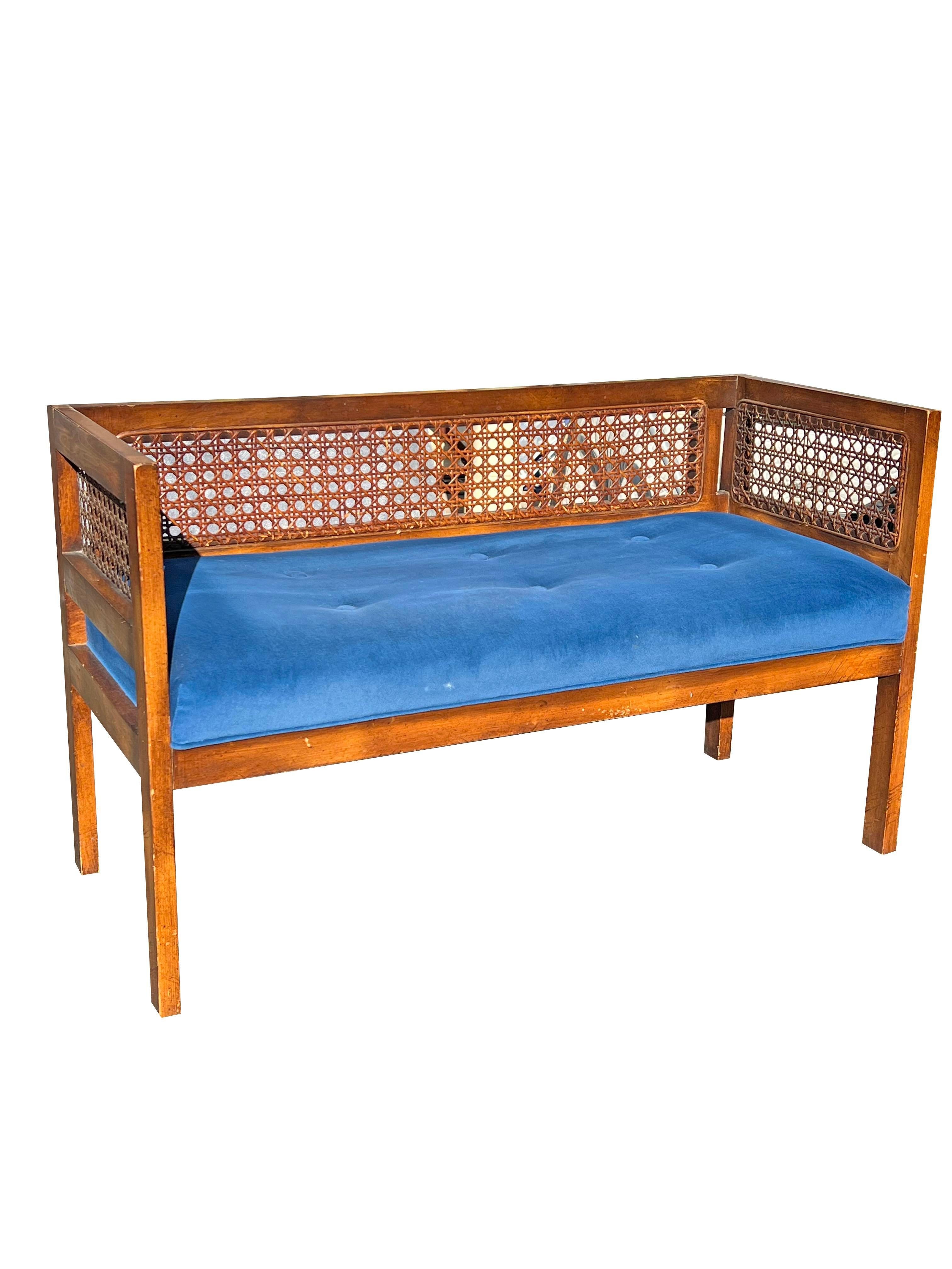 A Classic Vintage Bench: Comfortable and Stylish.

This charming vintage bench, upholstered in a classic blue fabric and accented with natural cane and wood, is a versatile piece that can complement a variety of interior styles. Its compact size