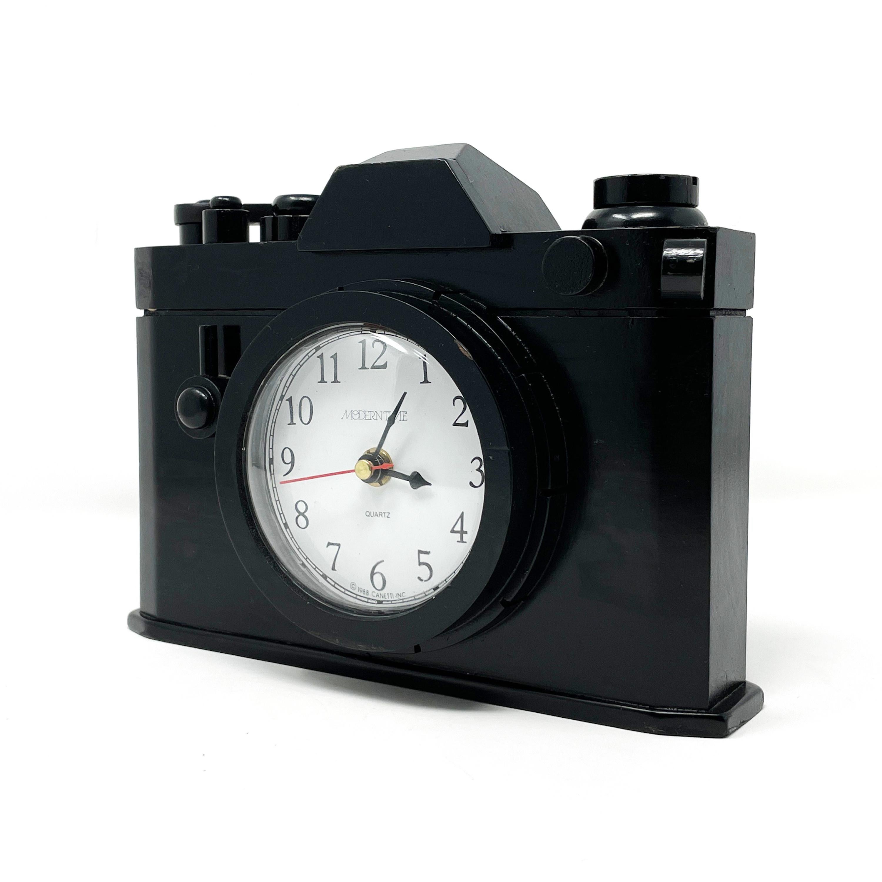 A postmodern clock by Canetti in the shape of a camera. Clock's face is set into the camera’s lens and body is solid wood with a moving film advance lever. In vintage condition with wear consistent with age and use, including one small wood piece