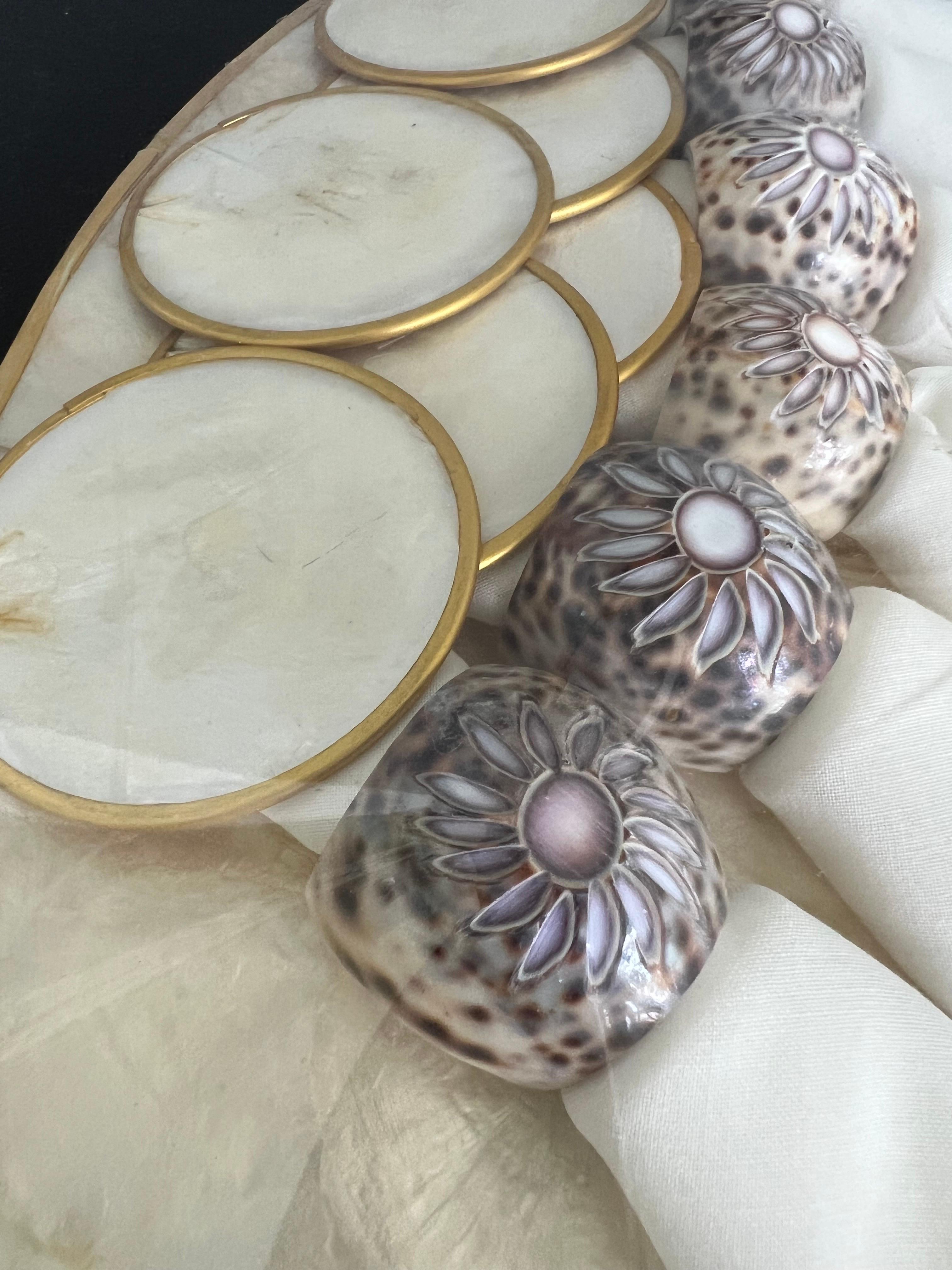 Still sealed in the original shrink wrap! This gorgeous vintage set of Capiz shell placemats, coasters, and napkin rings fashioned from Tiger Leopard Cowrie shells and matching cream-coloured napkins, comes straight from 1970s Philippines.Mint