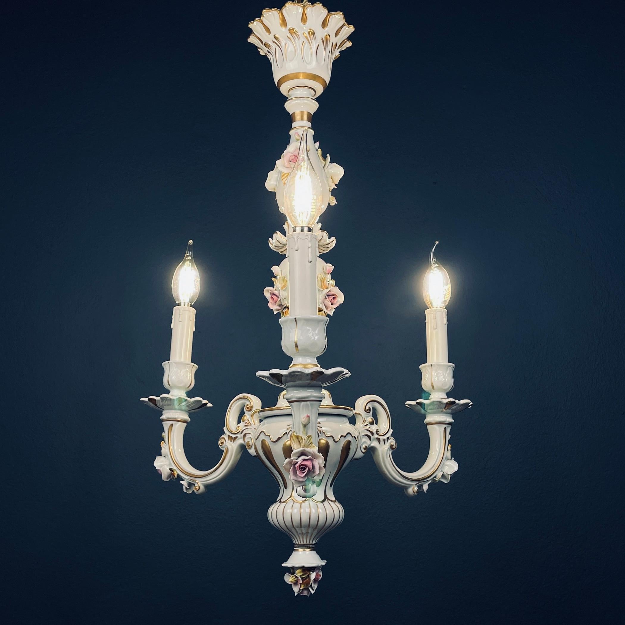 Elevate your living space with the timeless beauty of this vintage Capodimonte porcelain chandelier, crafted in Italy during the 1940s. This chandelier is adorned with intricate and hand-painted floral designs that exude a delicate and romantic