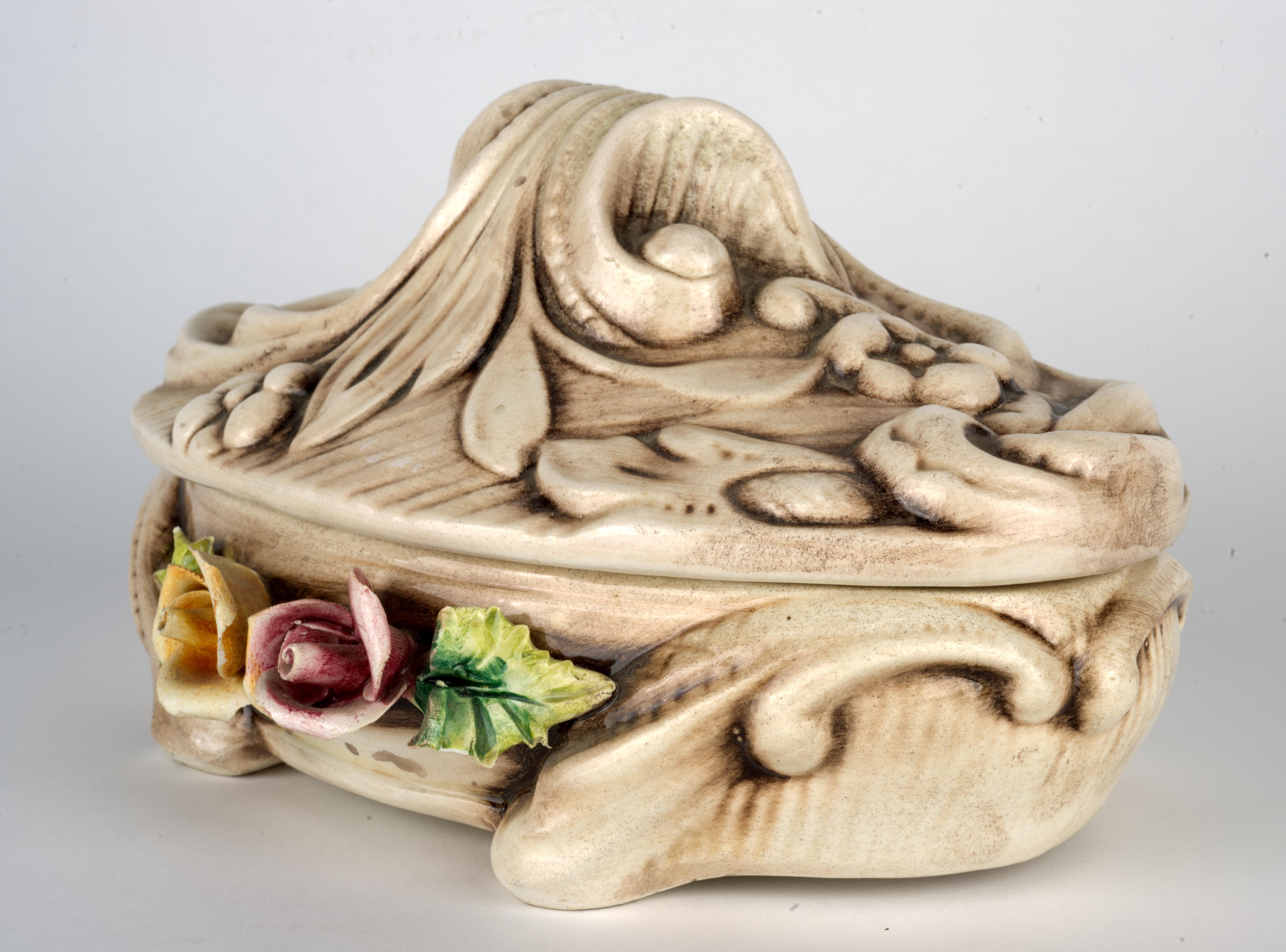  La caja de baratijas vintage ovalada cubierta de porcelana con tapa está decorada con flores esculpidas en la parte delantera de la caja y detalles en relieve de flores en la caja y la tapa. El relieve de la flor se acentúa con un suave tinte