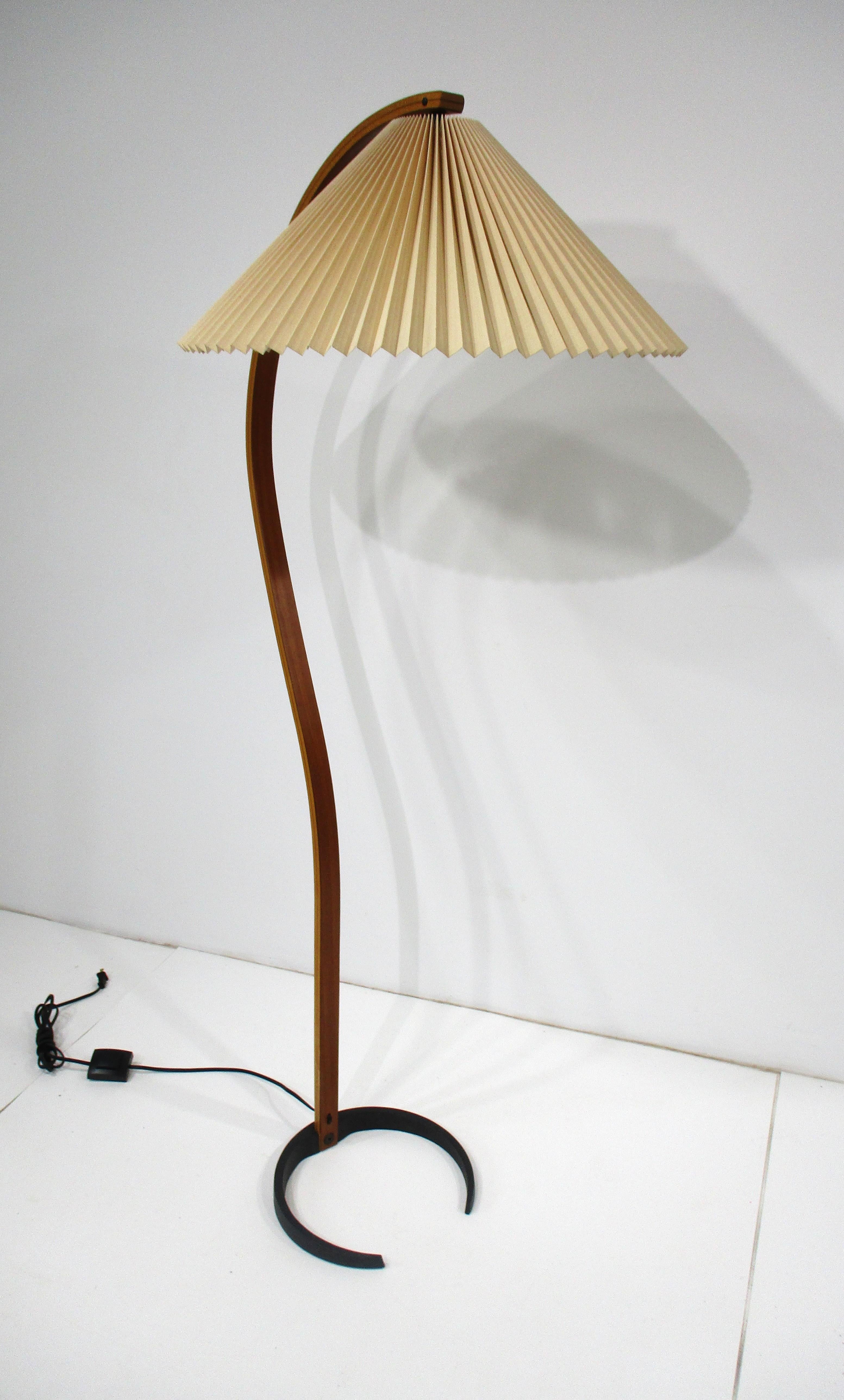 Lámpara de pie vintage con pantalla de madera laminada en forma de acordeón y pesada base de metal fundido negro . El interruptor de luz de pie facilita el control y conserva el nombre impreso del fabricante en la parte superior trasera de la base,