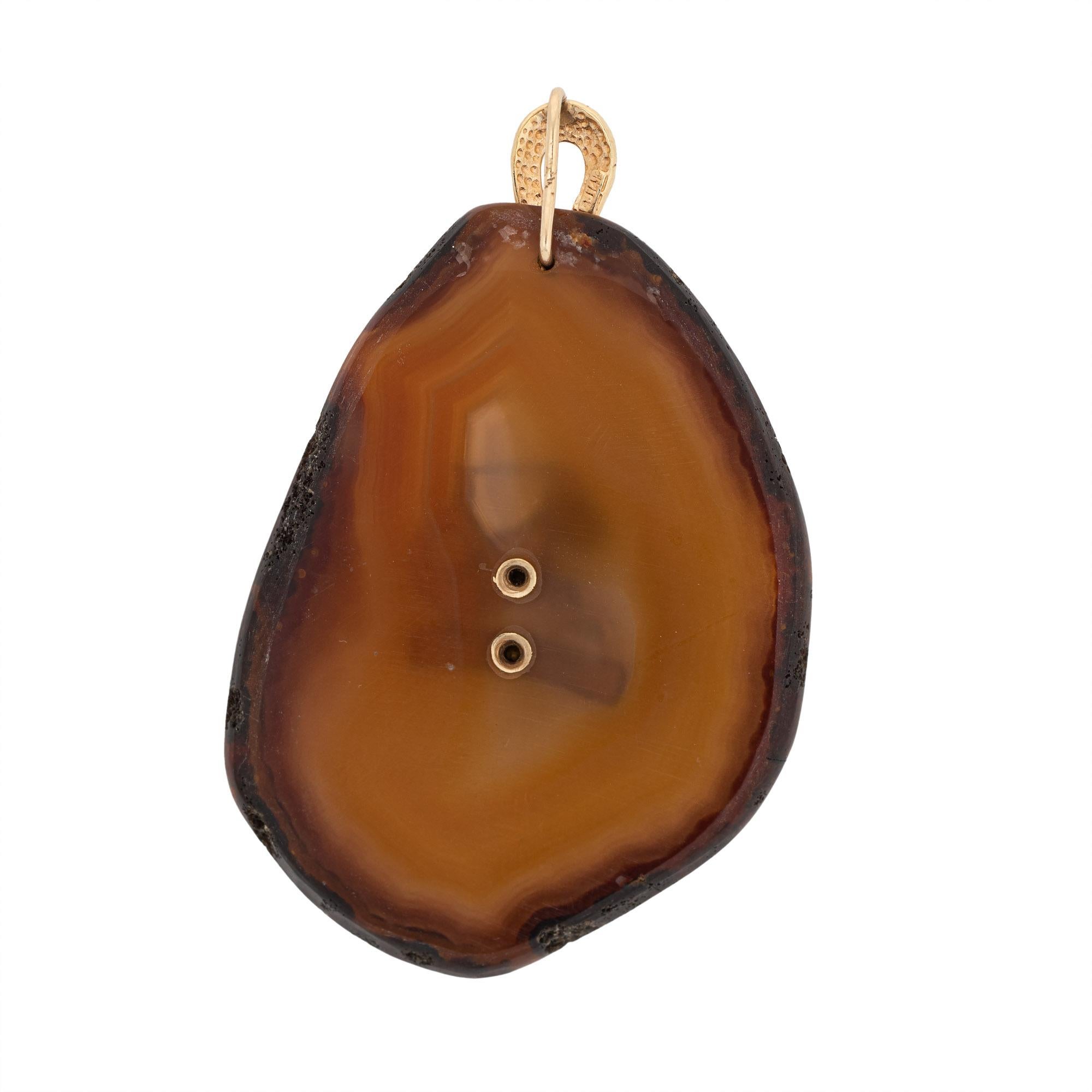 Finely detailed large Capricorn agate medallion pendant crafted in 14k yellow gold (circa 1970s).  

A large slice of freeform cut agate features a 14k gold set Capricorn zodiac center. The elaborate and bold design is a great example of 70s era