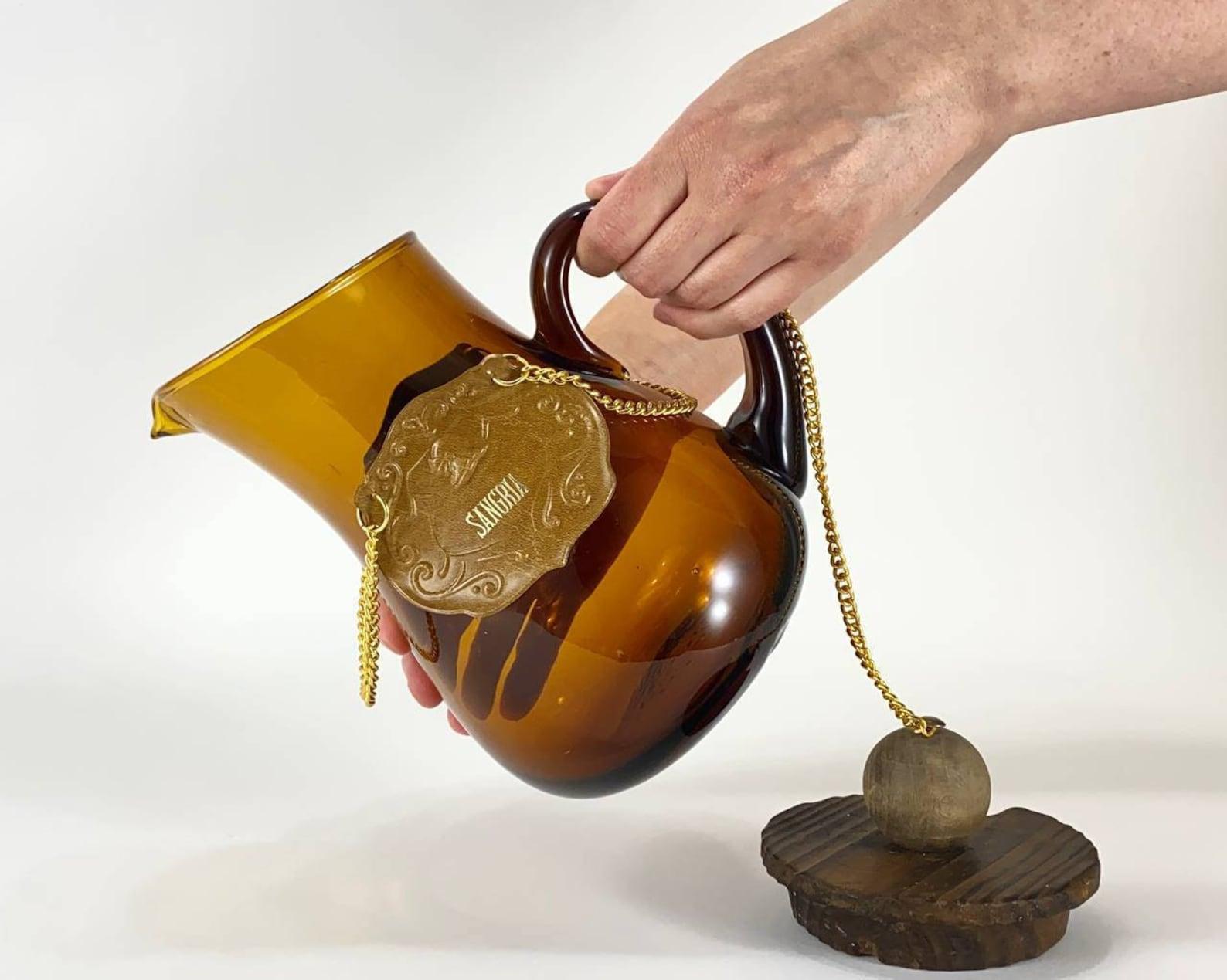 Vintage sangria pitcher or carafe in amber glass accompanied by its wooden stopper held by a golden chain. Leather tag. 

 Perfect for iced tea, water or sangria.

 An expensive, elite gift for a person who has everything! 

 Every collector