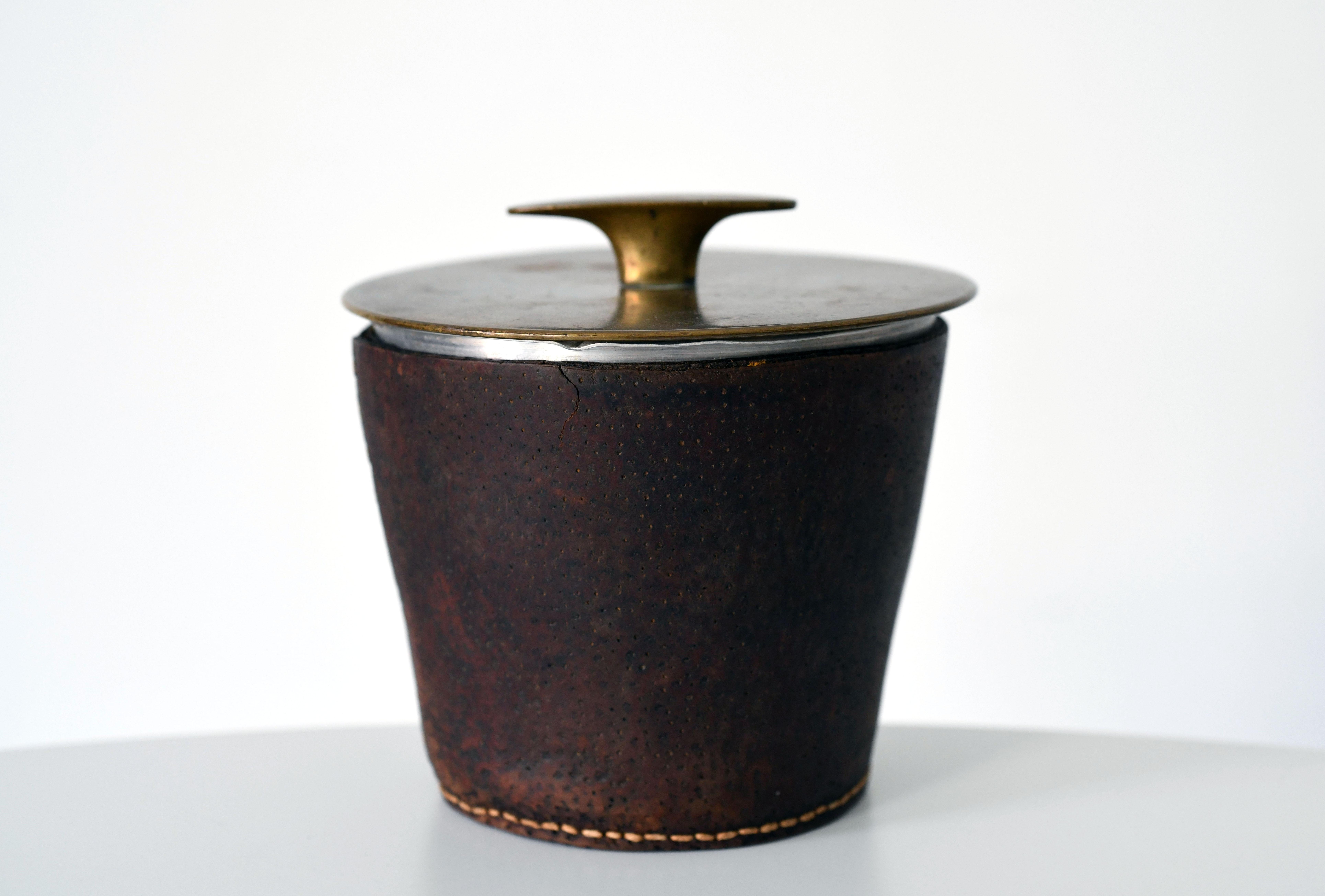 Rare tobacco jar by Austrian designer Carl Auböck.  Age related wear to leather.  Signature mark to lid.