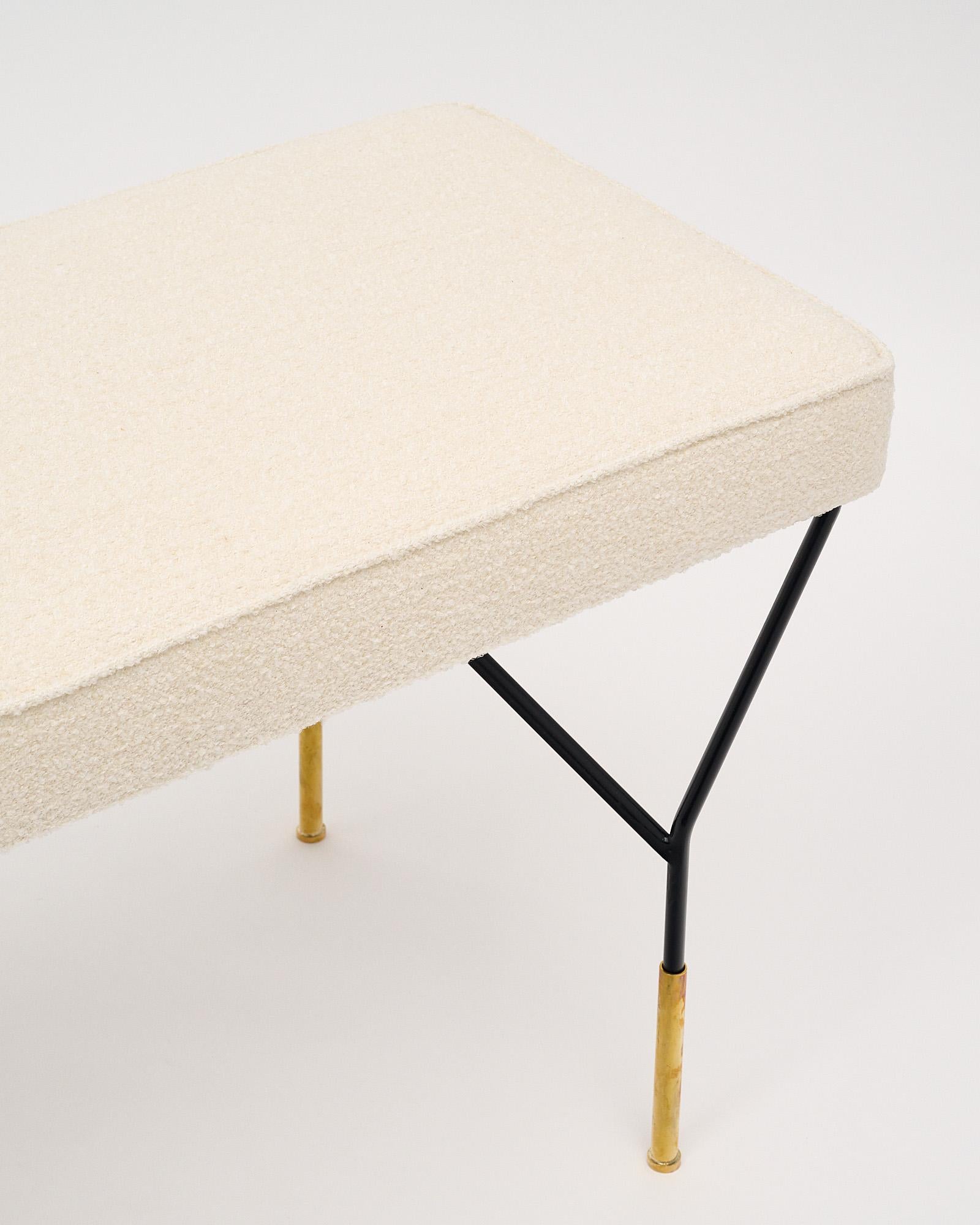 A dynamic bench in the style of Carlo di Carli. It features a black lacquered steel base with gilt brass feet. It has been newly upholstered in a white boucle fabric.
