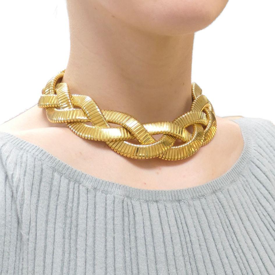 This vintage 18k gold braided tubogas choker necklace by Carlo Weingrill, circa 1980s, is a bold and luxurious piece. The necklace measures 16 inches in length and 1 inch in width, weighing an impressive 218.8 grams. The tubogas design is