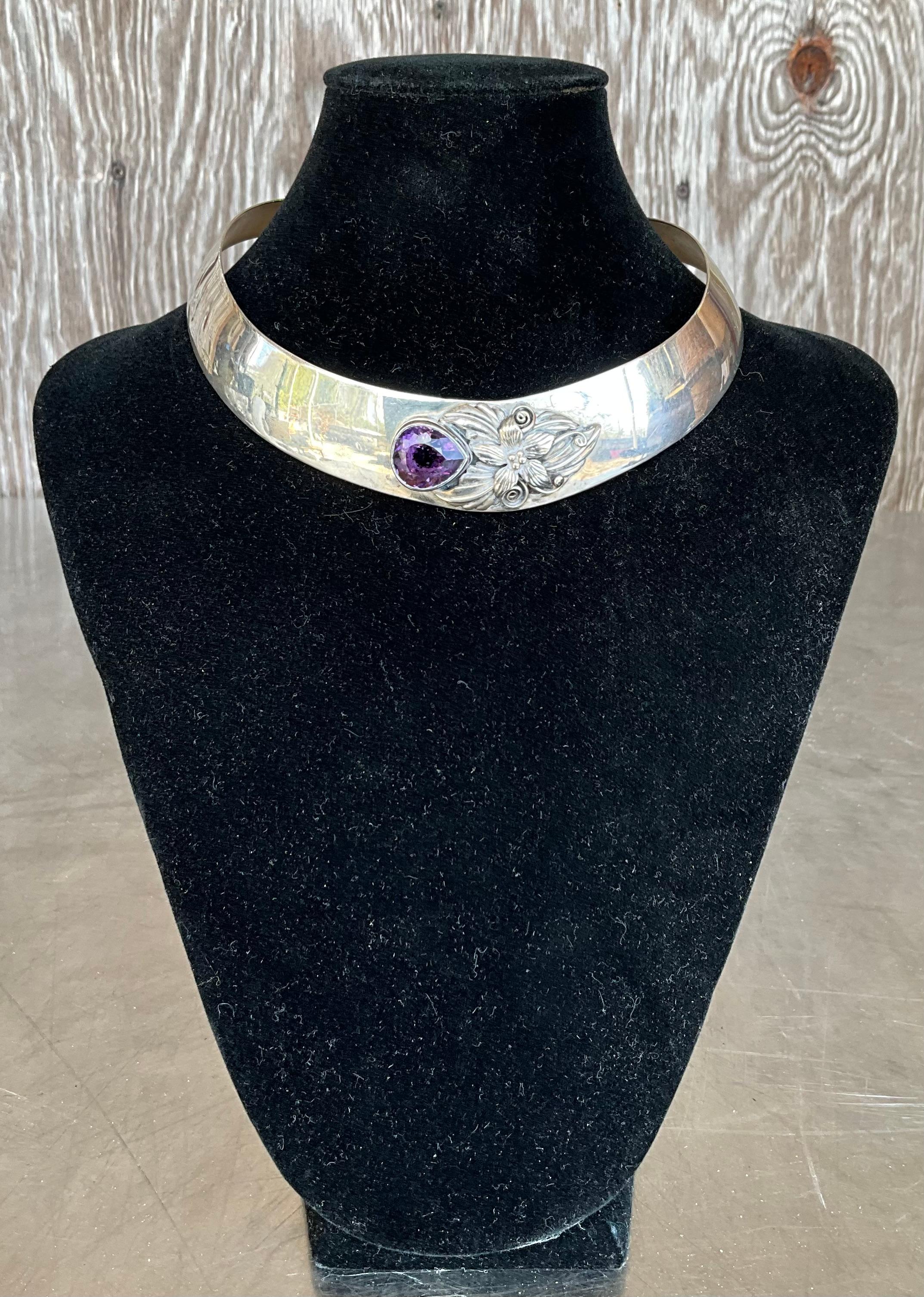 A Vintage Carol Felley Sterling Silver & Amethyst Bib Choker Necklace is a stunning piece of jewelry that exemplifies the unique artistry and craftsmanship of the renowned designer Carol Feeley. 

This necklace features a striking bib choker design,