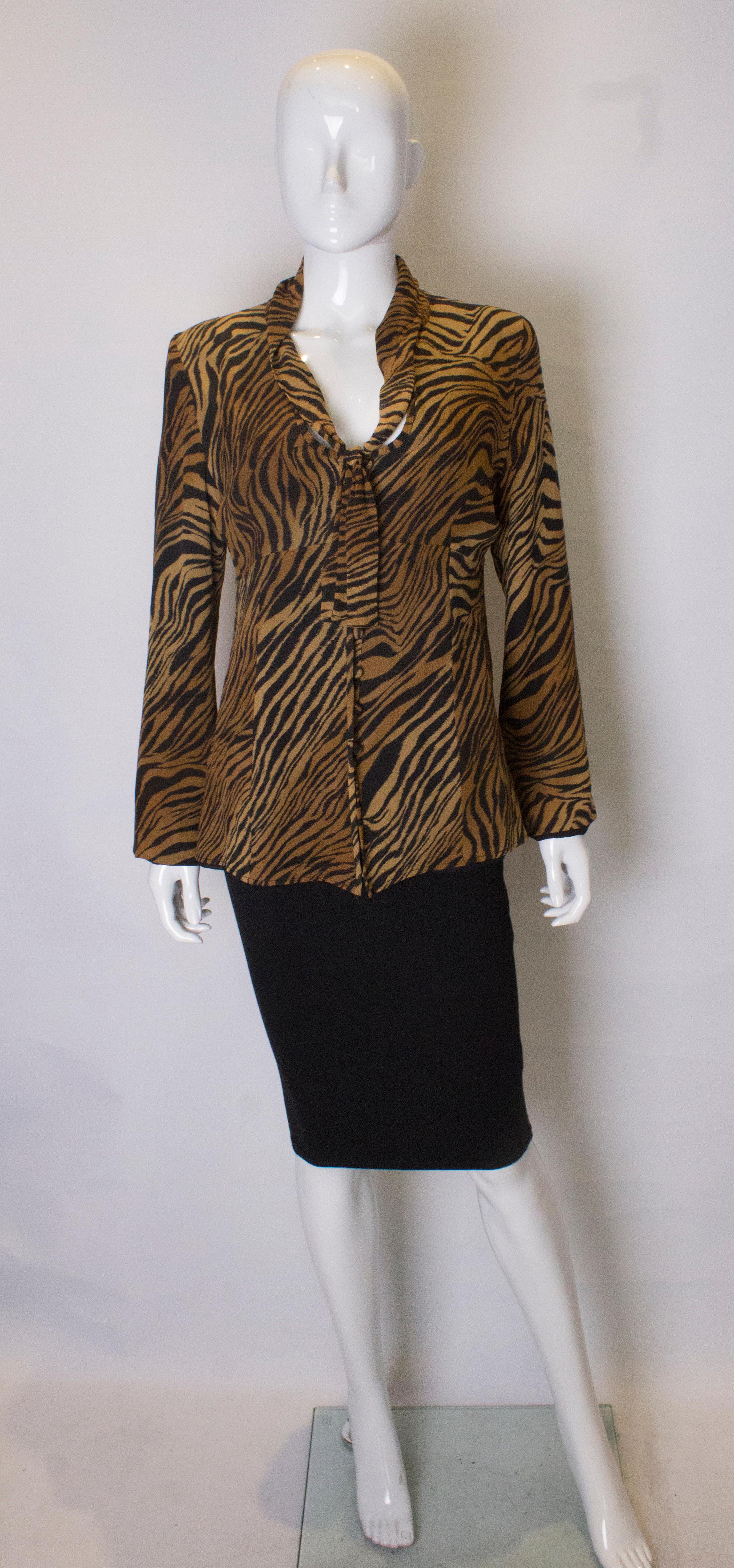 A great , head turning animal print silk blouse by Caroline Charles. The blouse has a  v neckline and neck tie and is fully lined.